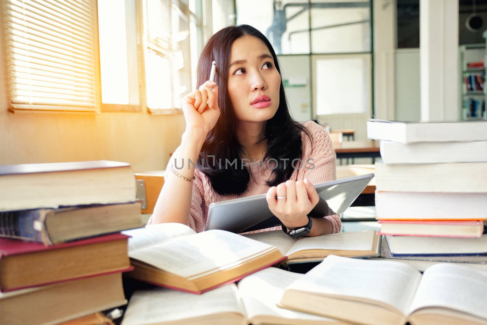 Young woman using tablet in a library by Surasak