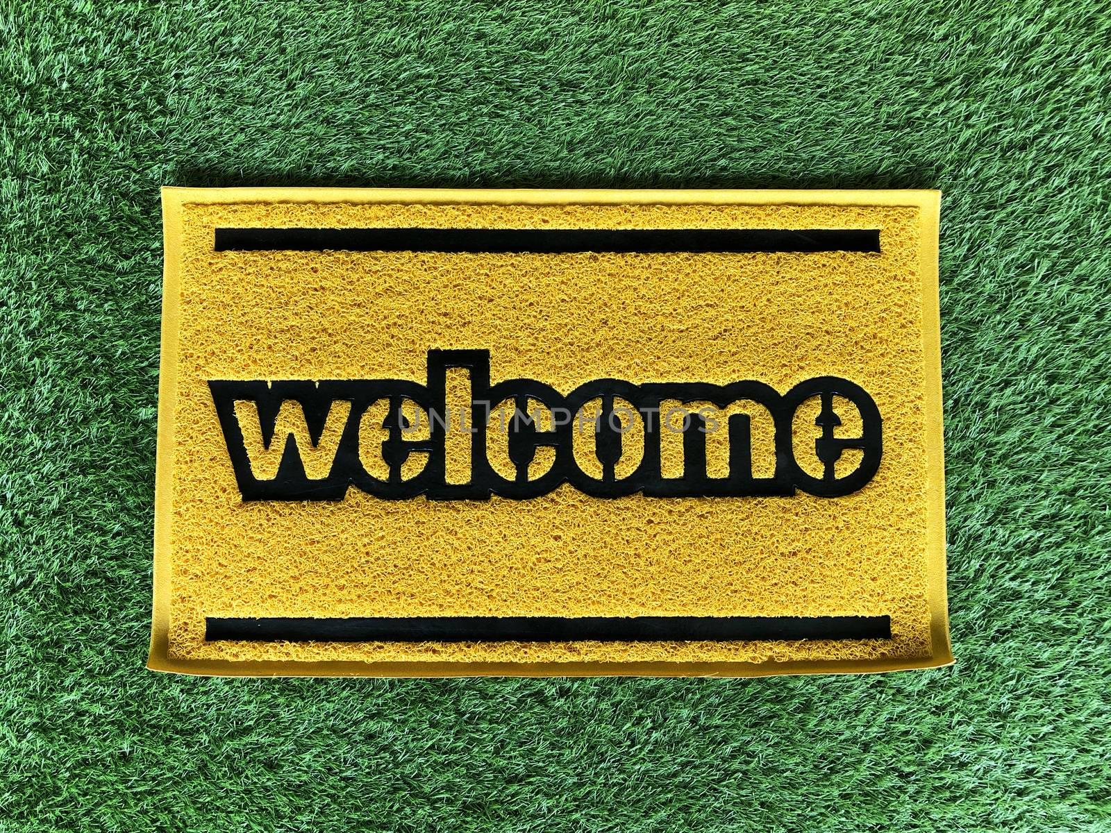 Yellow welcome word of green foot scraper.Microfiber fabric texture background.