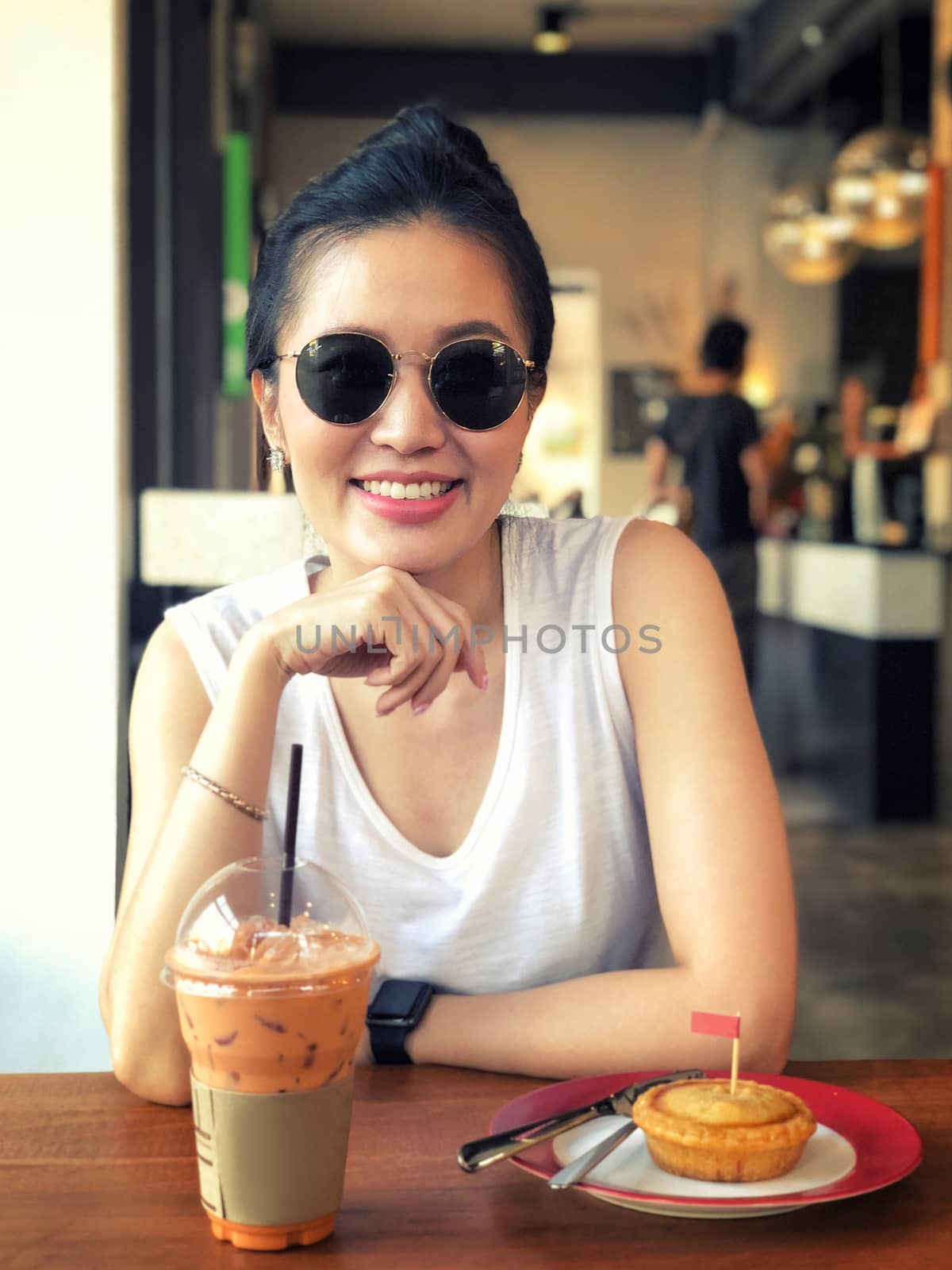Portrait of young woman drinking tea and looking with smile out of the coffee shop 