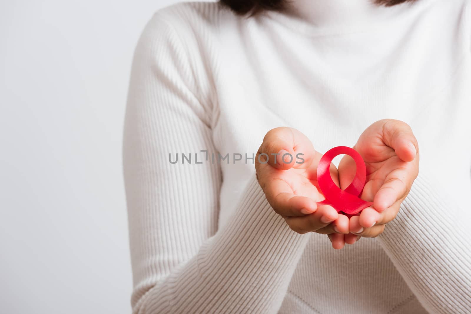 woman holding pink breast cancer awareness ribbon on hands by Sorapop
