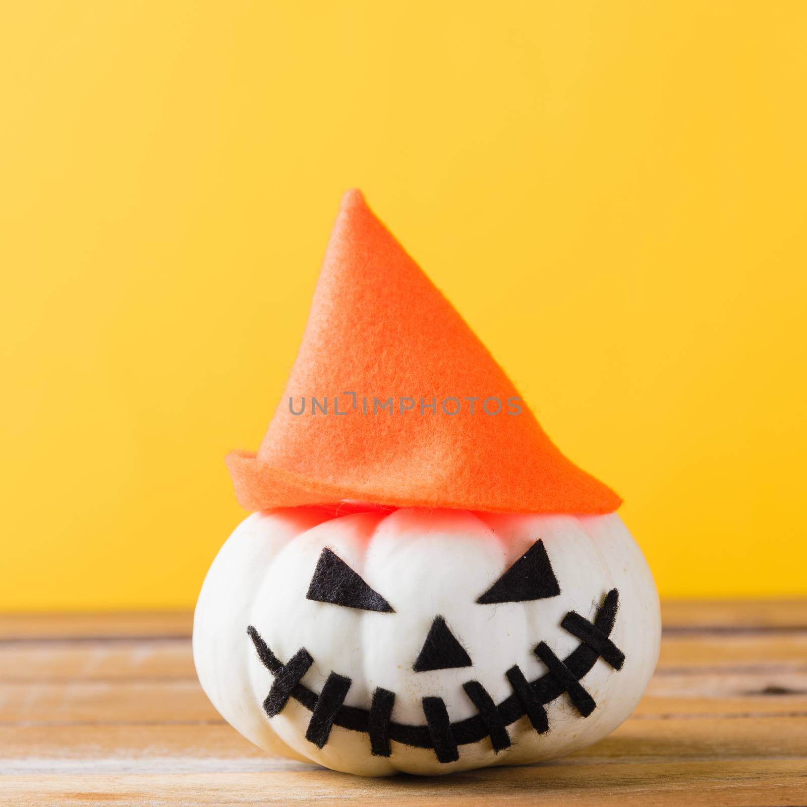 Funny Halloween day decoration party, closeup halloween pumpkin head jack o lantern smile scary on wooden and copy space, studio shot isolated yellow background, Happy holiday concept