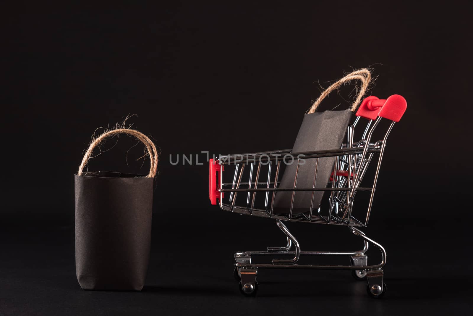Black Friday sale shopping concept, Black shopping bags in a shopping cart, studio shot isolated on black background