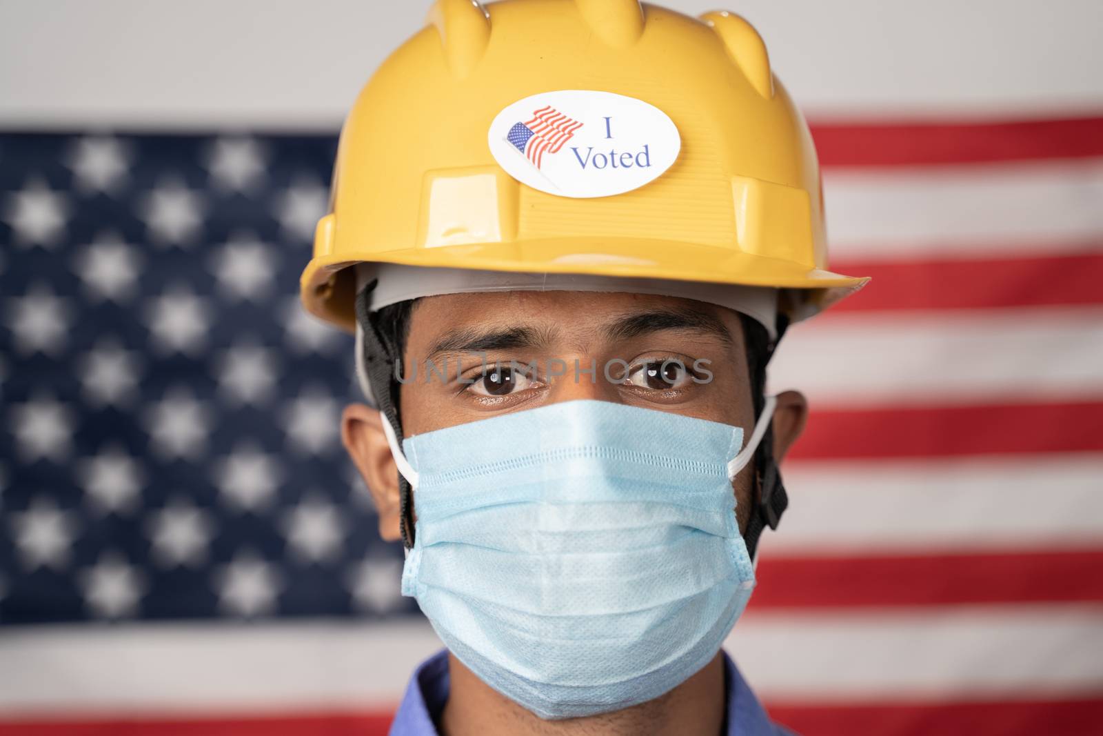 Head shot, I voted sticker on worker hardhat with US flag as background - Concept of USA elections and voting