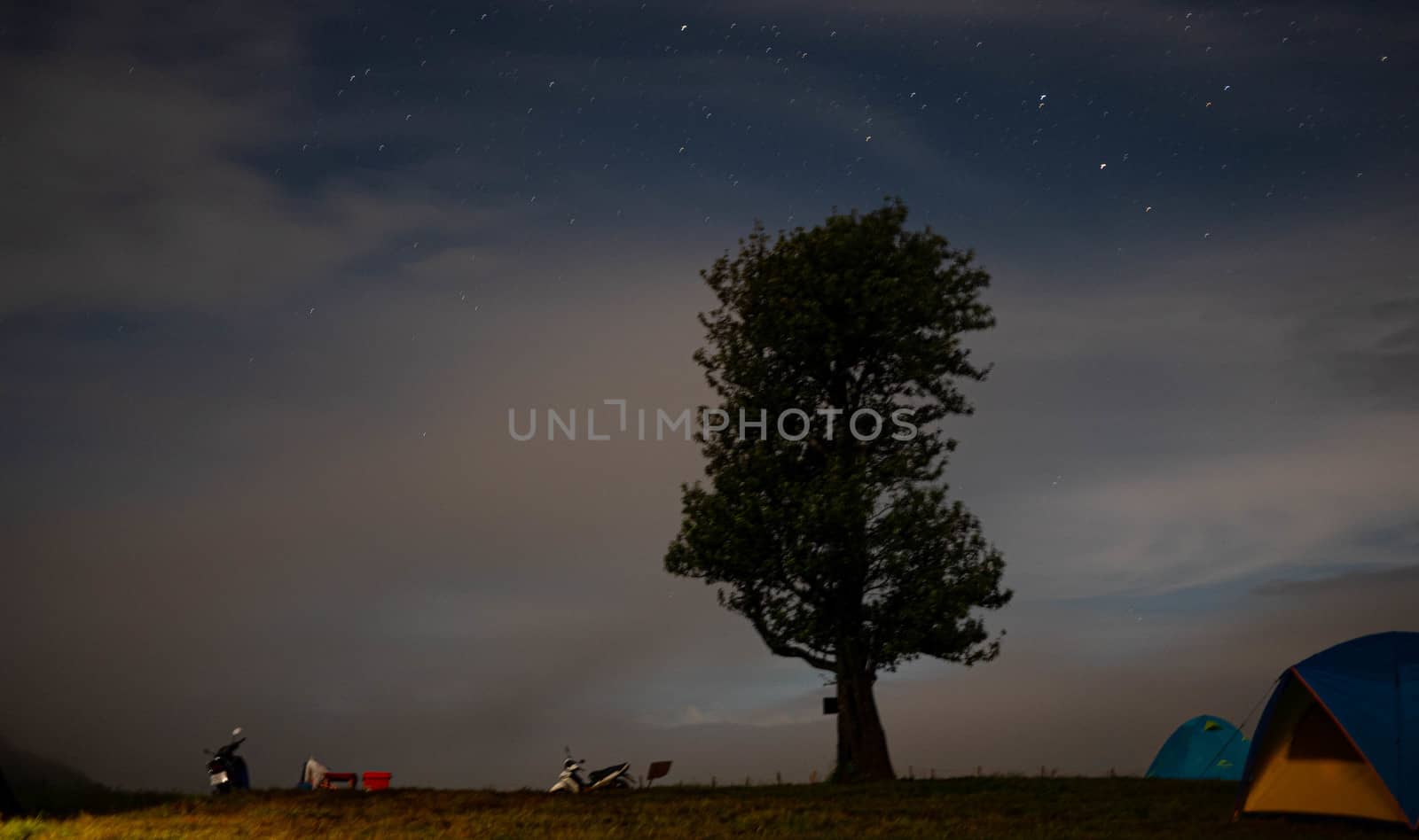 Starry night mountain landscape with tents in the mountains unde by TEERASAK