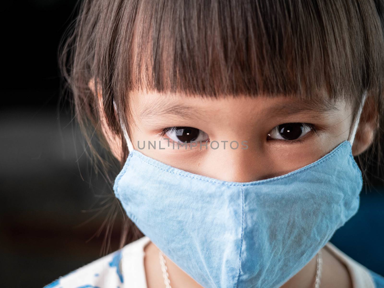 Asian child girl wearing face mask to protect her from coronavir by TEERASAK
