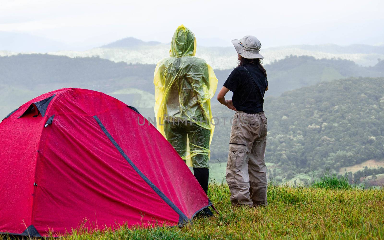 Couple stand at tent and enjoying the beautiful foggy mornig on the mountain top. Doi Mae Tho, Chiang Mai, Thailand.