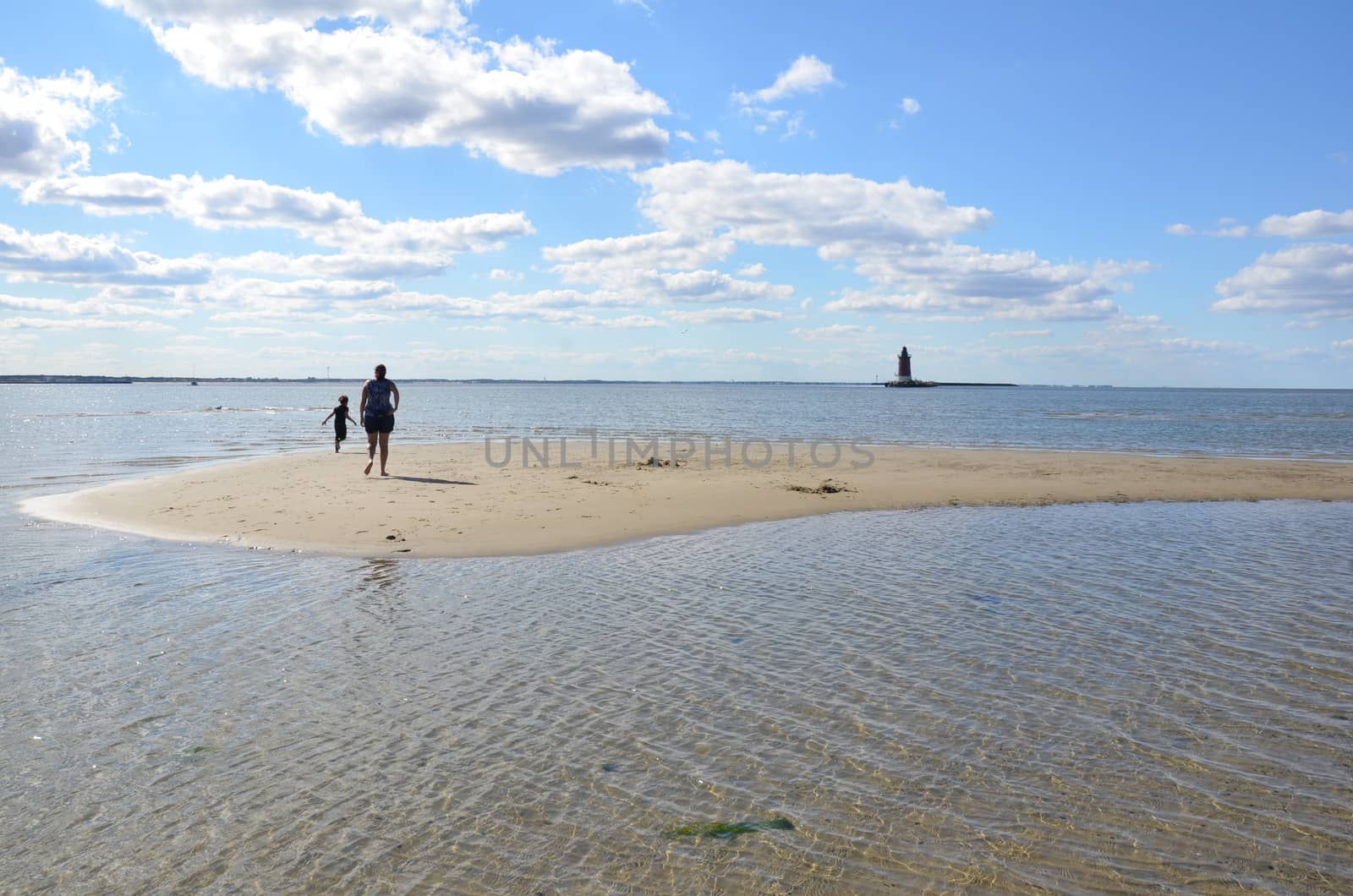 mother and child playing on beach with lighthouse by stockphotofan1