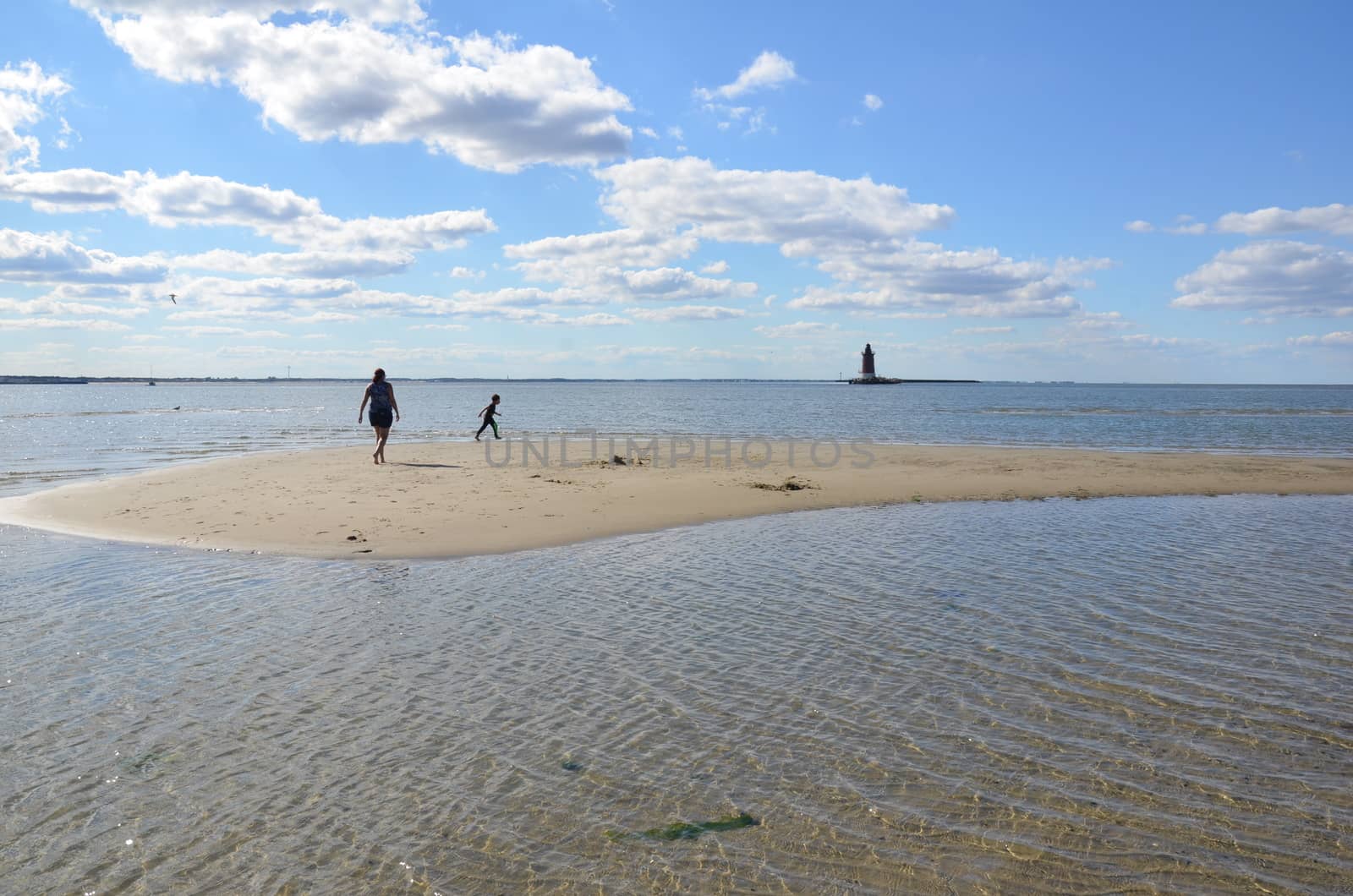 mother and child playing on beach with water and lighthouse