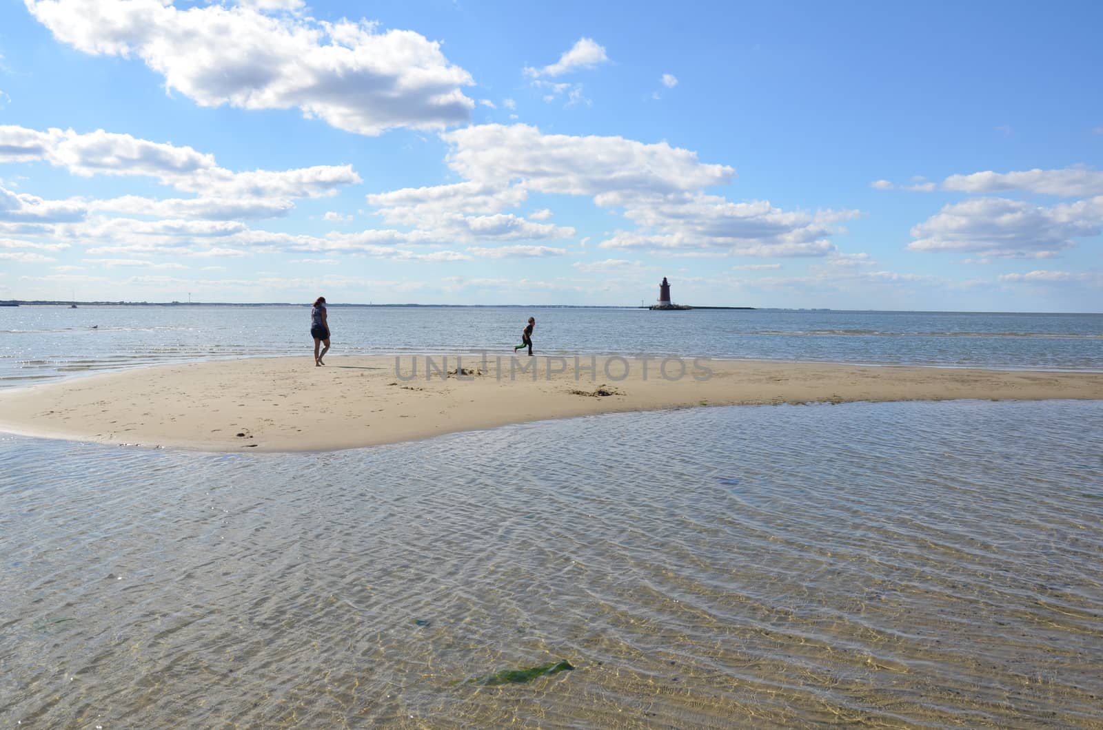 mother and child playing on beach with lighthouse by stockphotofan1