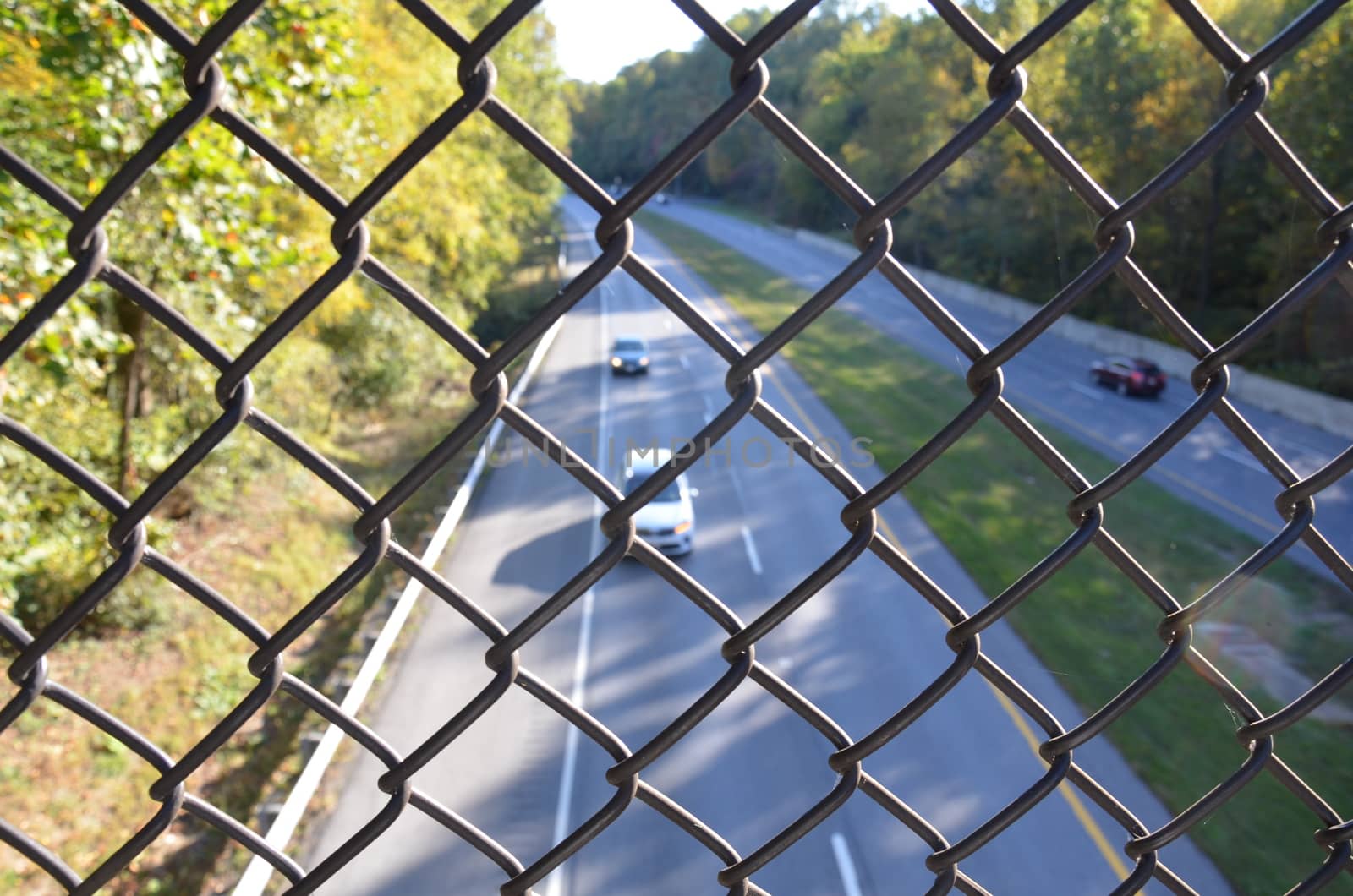 metal chain link fence over highway or road with cars