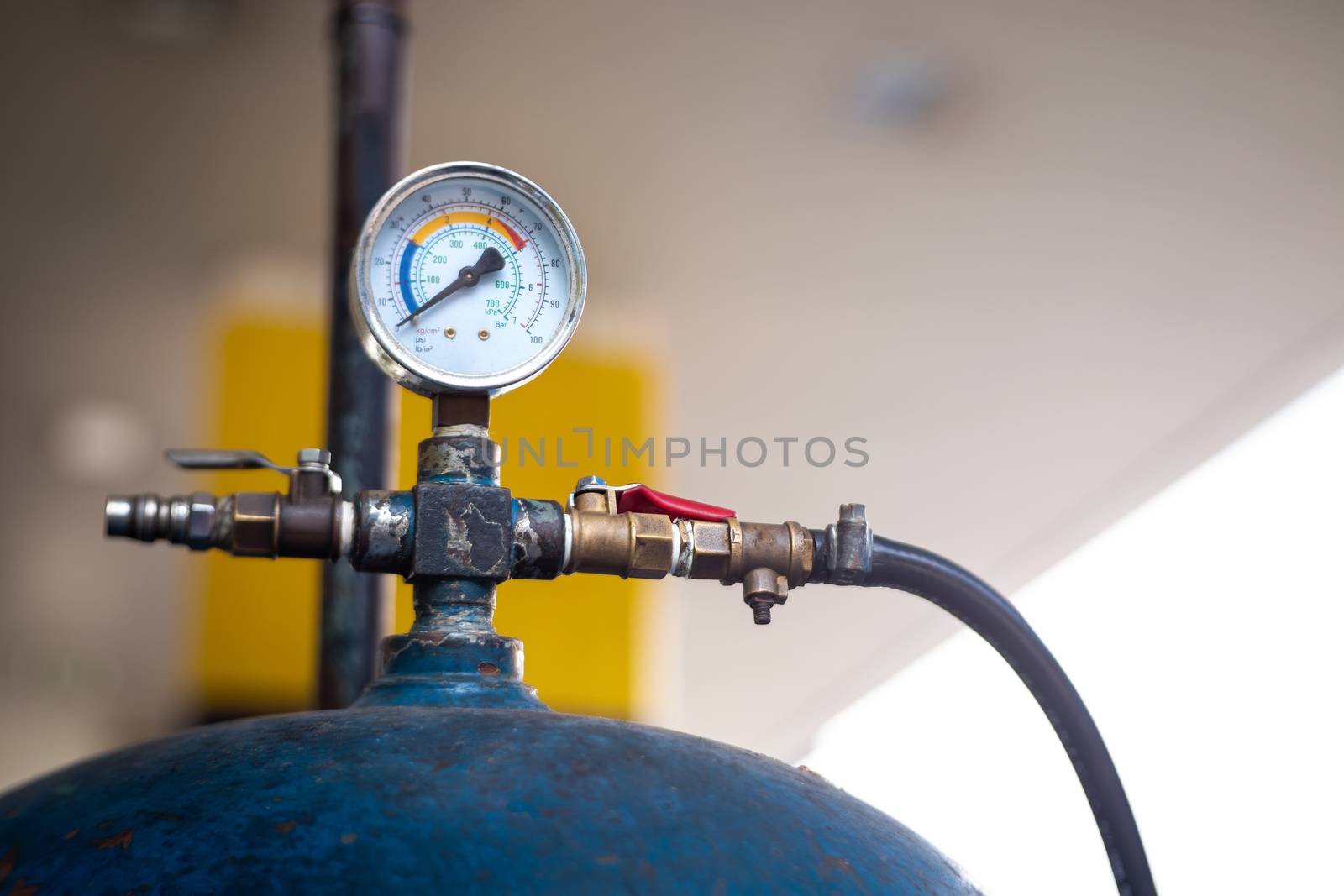 detail of tire Inflator in gas station, old air pressure tank with guage and valve used to put air into the tire, shallow depth of field