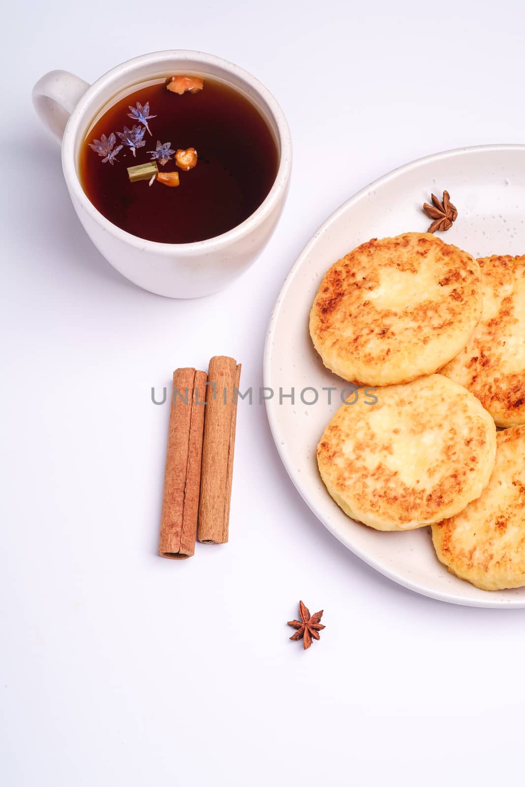 Cottage cheese fritters with hot black aromatic tea, Christmas breakfast mood with anise and cinnamon on white background, top view
