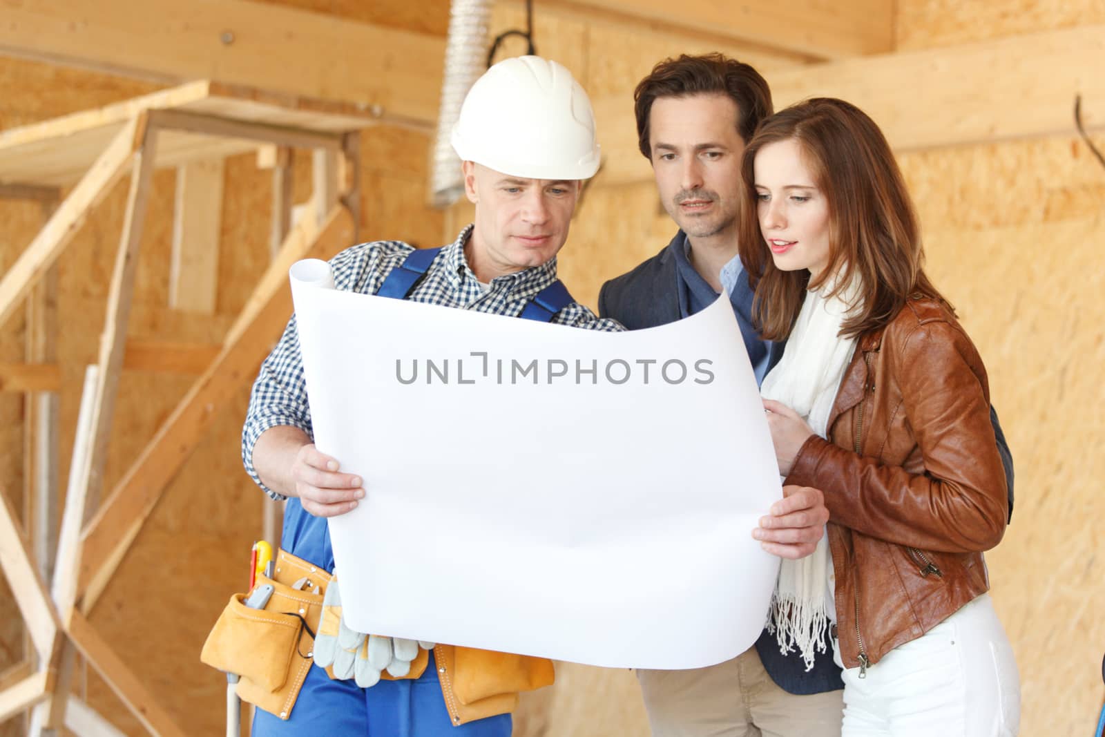 Foreman showing house design construction plan to a happy young couple new house real estate concept