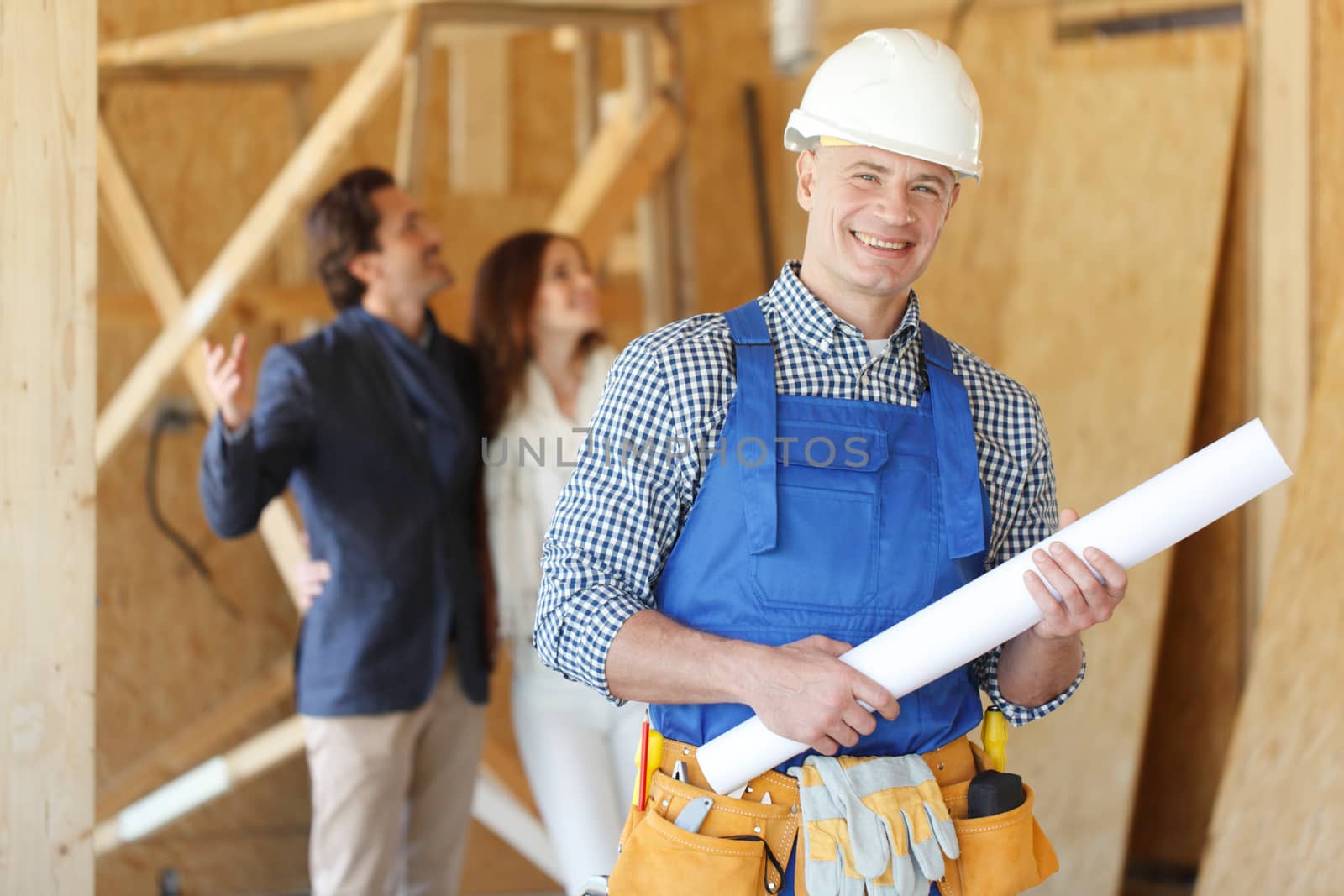 Foreman showing house design construction plan to a happy young couple new house real estate concept