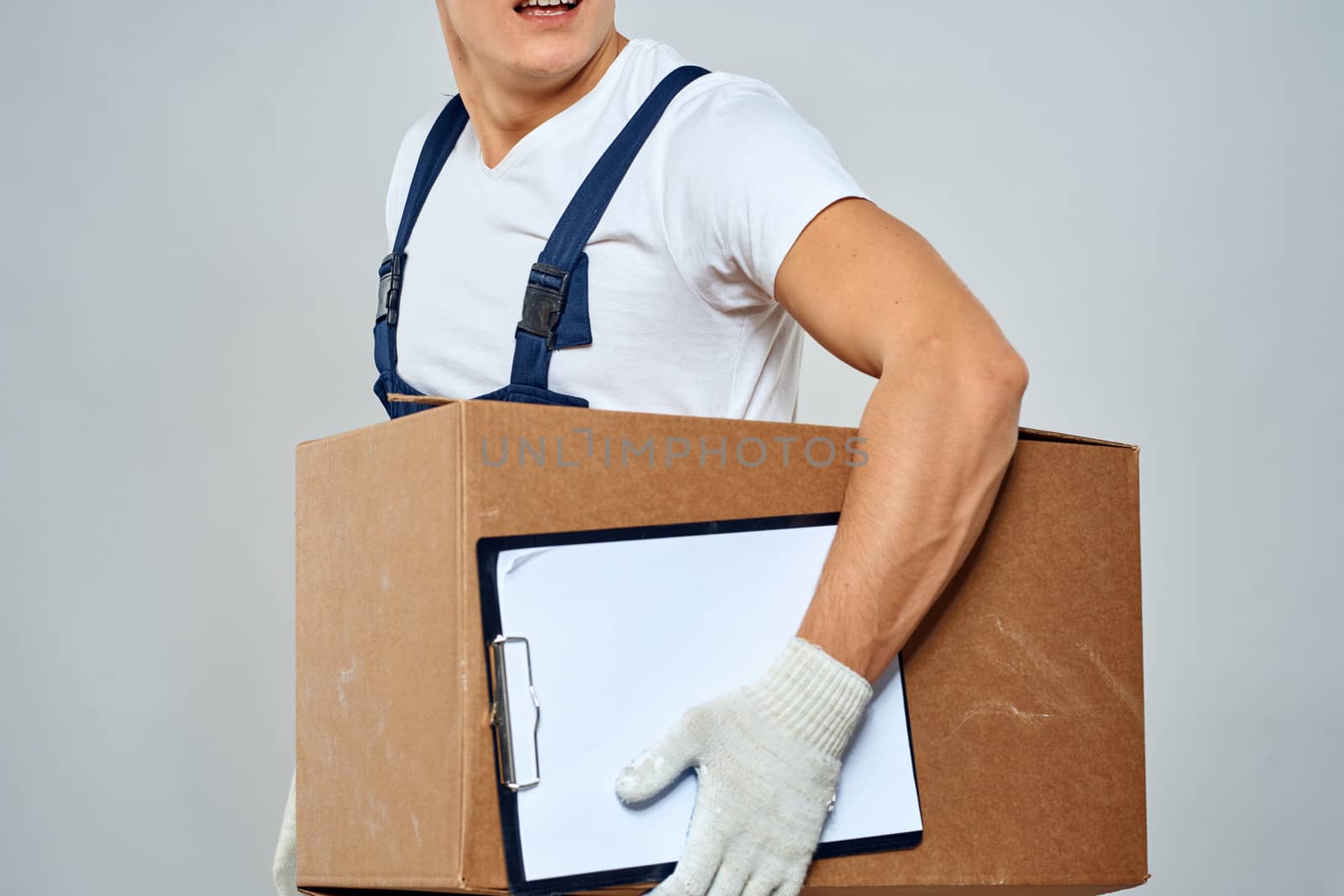 Man worker with box in hands delivery loading service work light background by SHOTPRIME