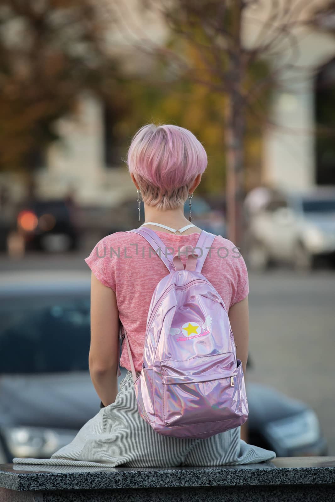 A girl with a stylish appearance. A girl with creative looks. A lonely girl sits near the entrance to the subway. Youth modern style of clothing. A breakthrough in modern fashion.