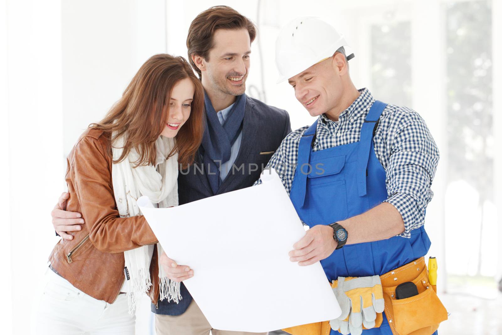 Foreman showing house design construction plan to a happy young couple new house real estate concept