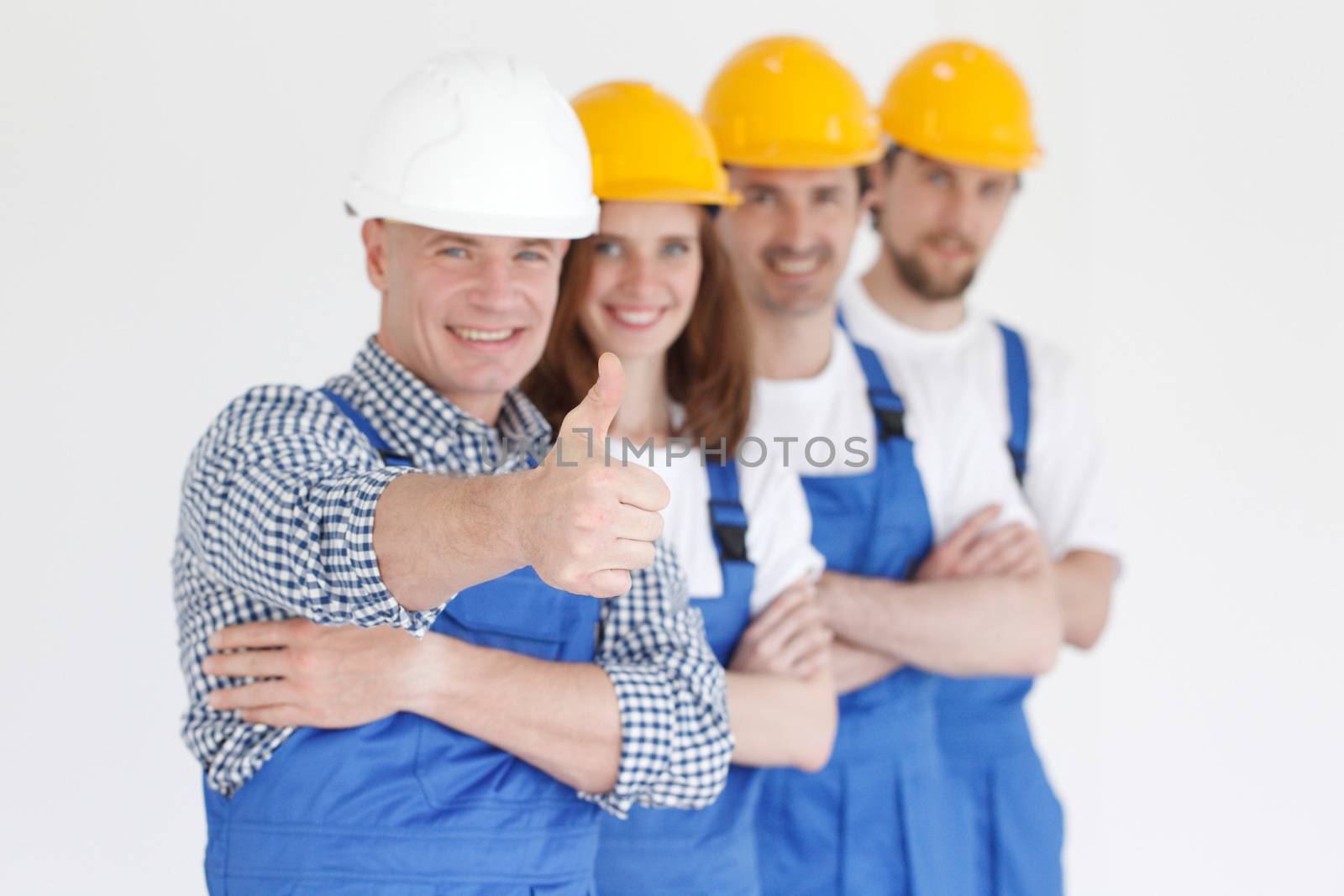 Team of happy workers in uniform ready to work, man showing thumb up sign
