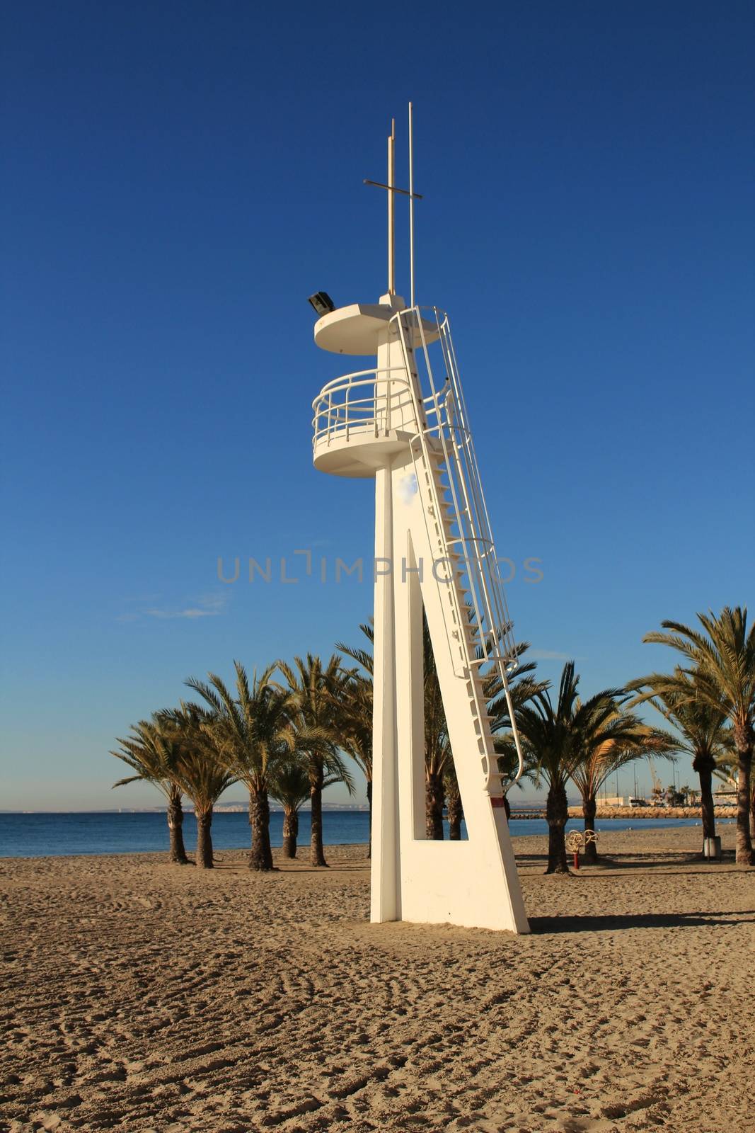 Santa Pola, Spain- February 16, 2018: Lifeguard tower on a quiet and lonely beach in a sunny day in southern Spain, Alicante. Palm trees in the background.
