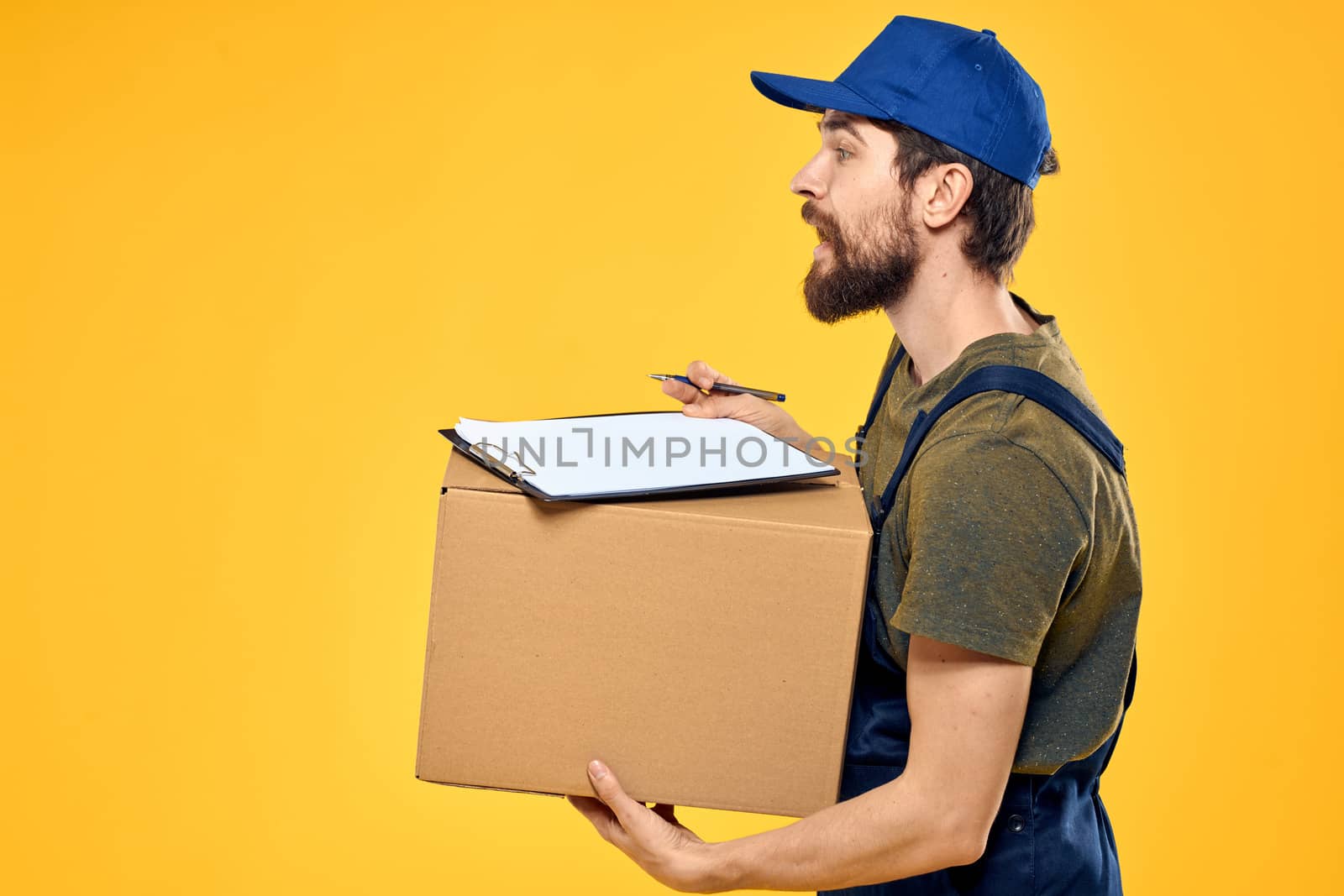 Worker male courier delivering boxes packaging documents yellow background. High quality photo