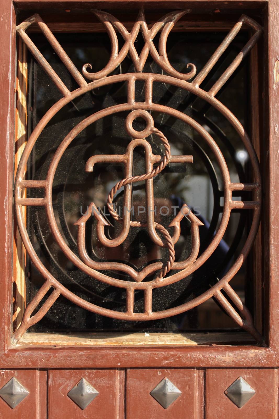 Brown wooden door with anchor detail in wrought iron door in Alicante, Spain