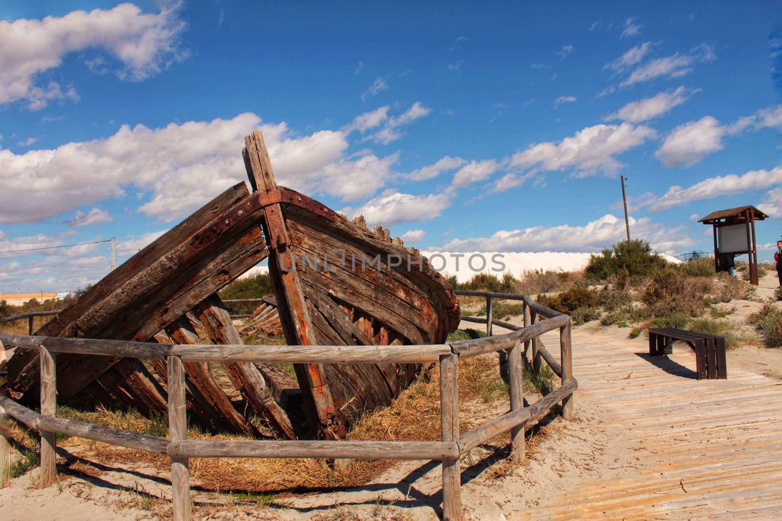 Old abandoned boat on the beach in Santa Pola. Salinas in the background under blue sky