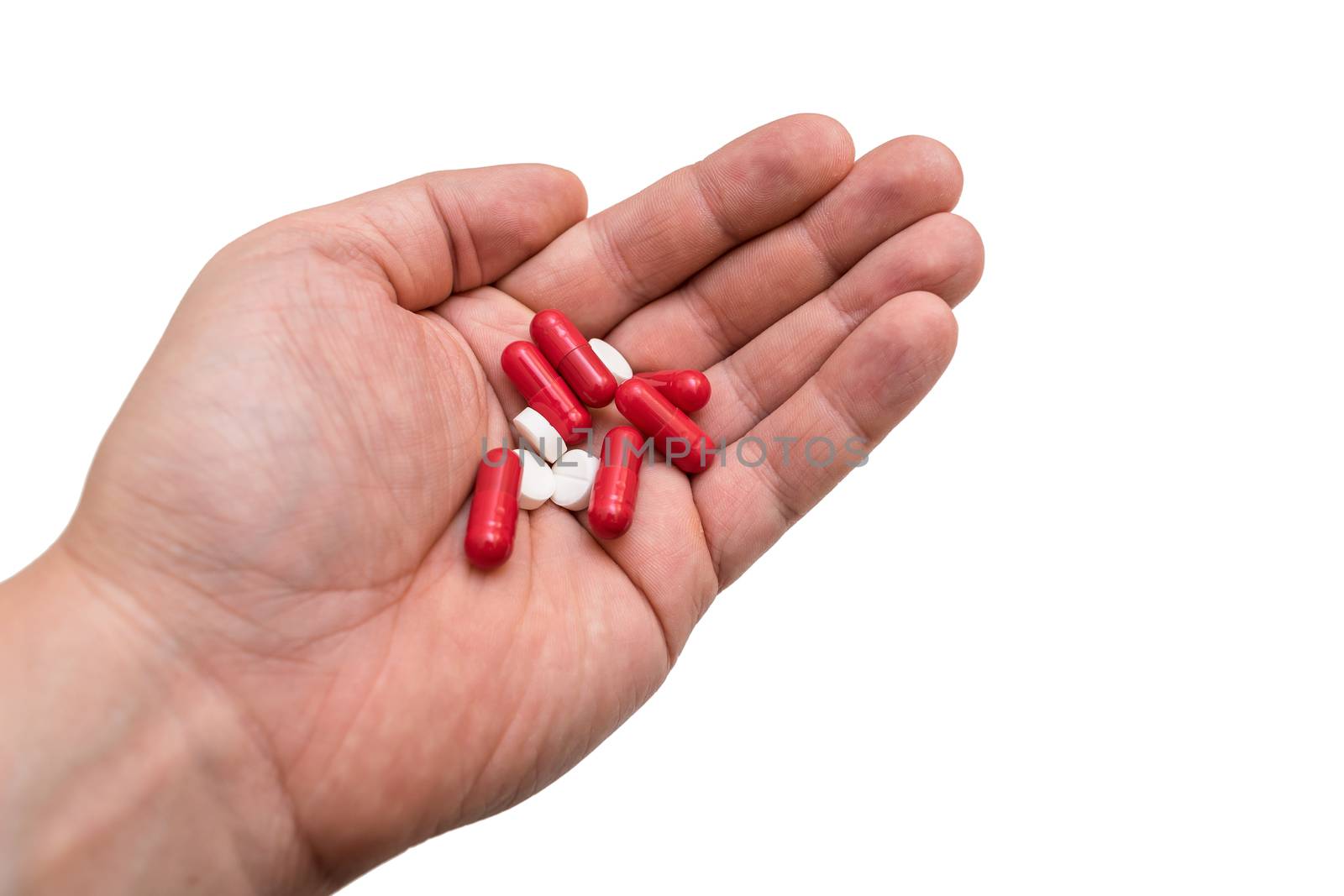 Different pills in the hands of a man close up on a white background