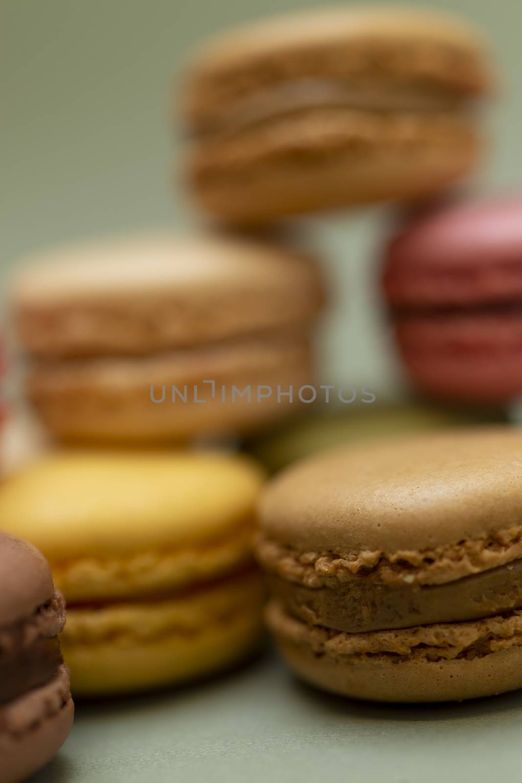 Pile of colored tasty macaroons over a green background.