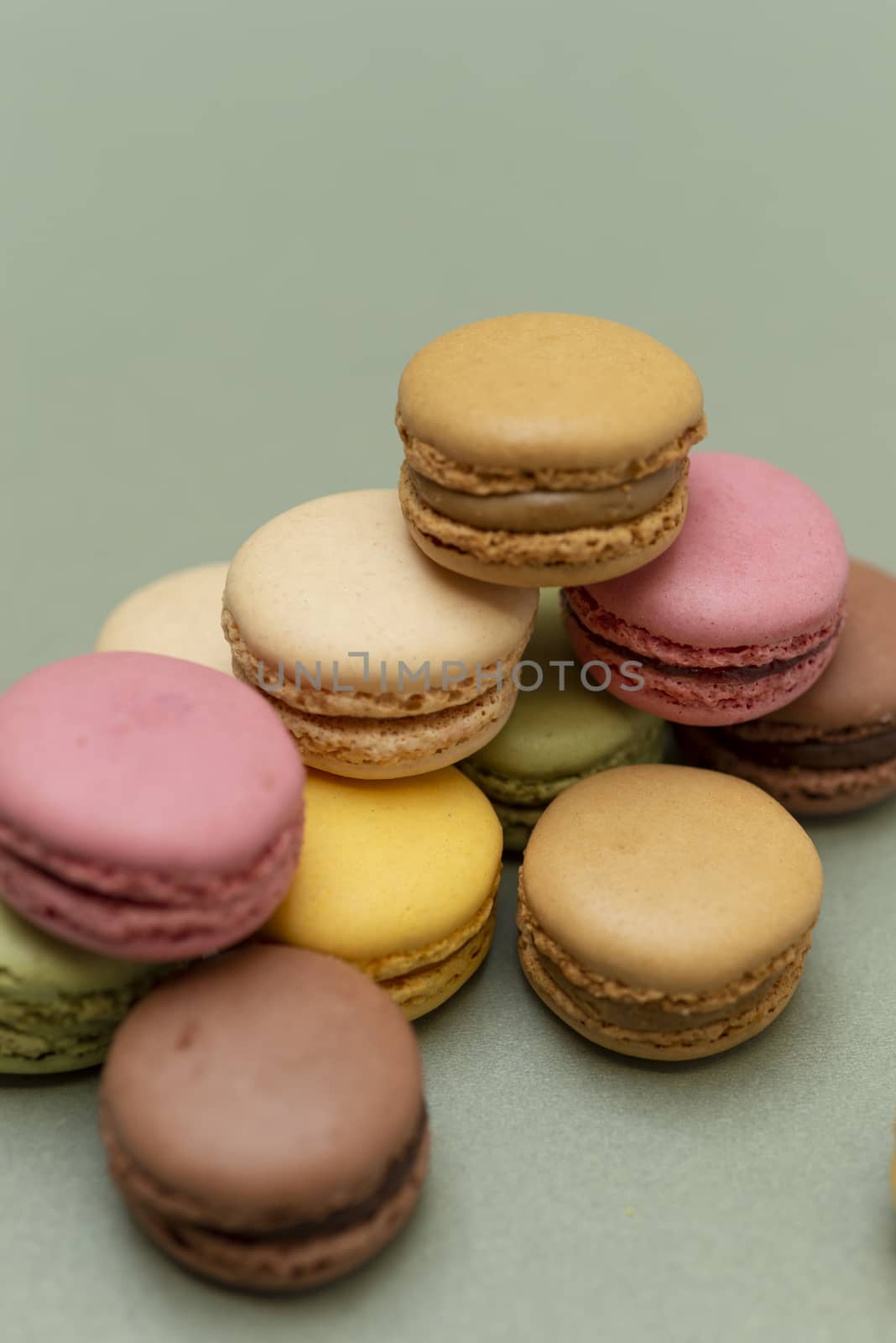 Assorted colored tasty macaroons over a green background.