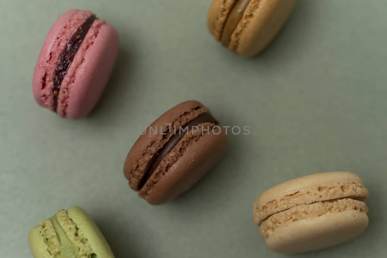 Assorted colored tasty macaroons over a green background.