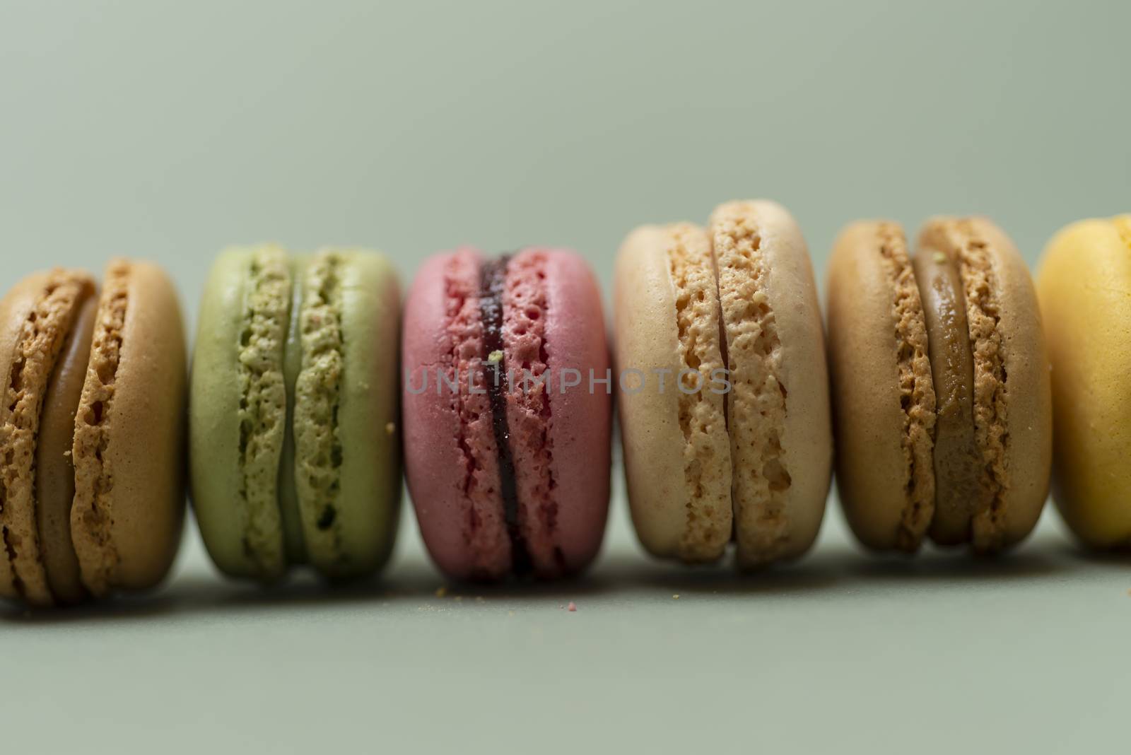 Assorted colored tasty macaroons over a green background.