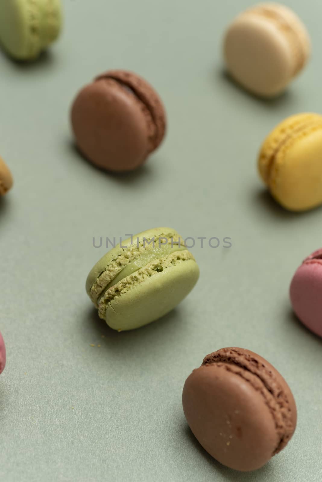 Assorted colored tasty macaroons over a green background.