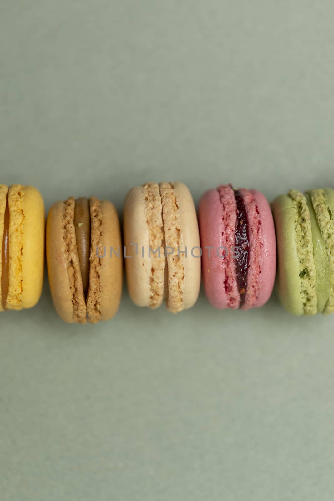 Assorted colored tasty macaroons over a green background.