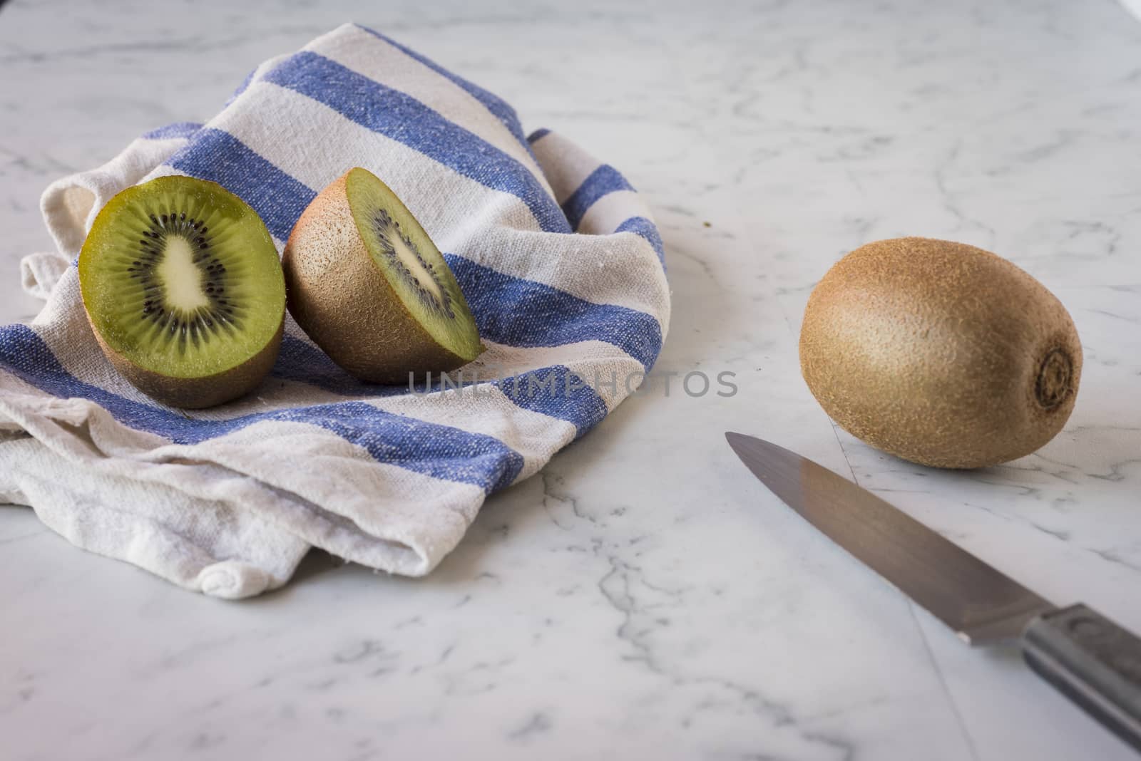 Two green and fresh kiwis on marble surface