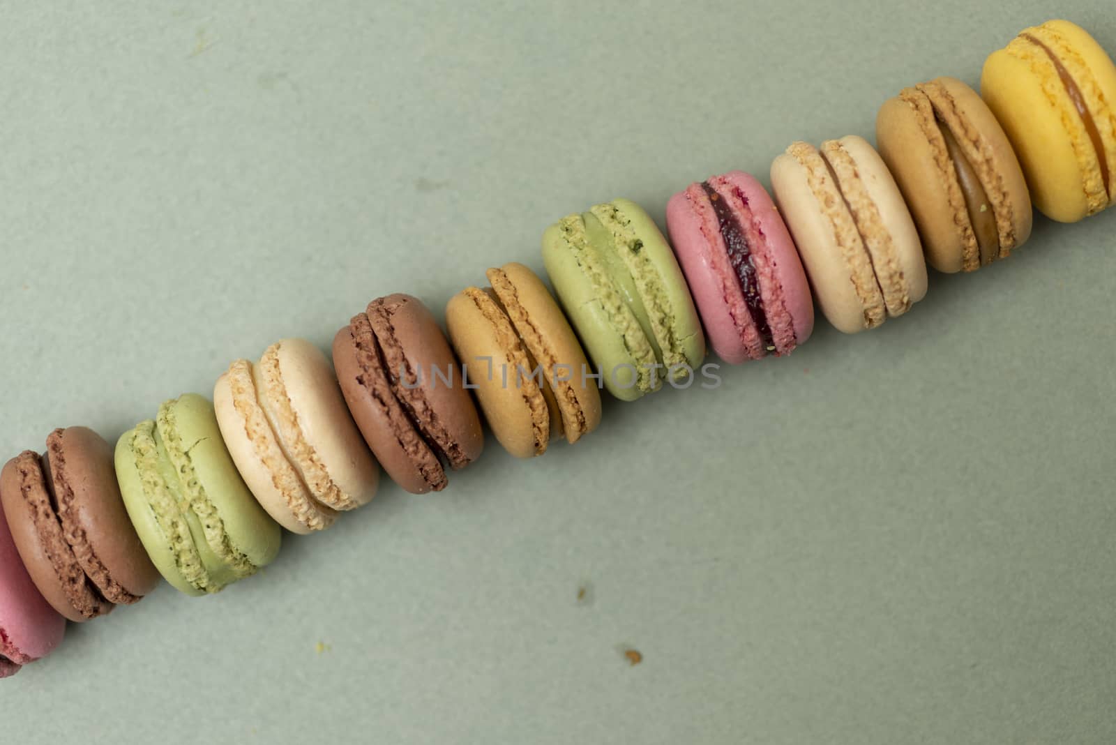 Assorted colored tasty macaroons over a green background.