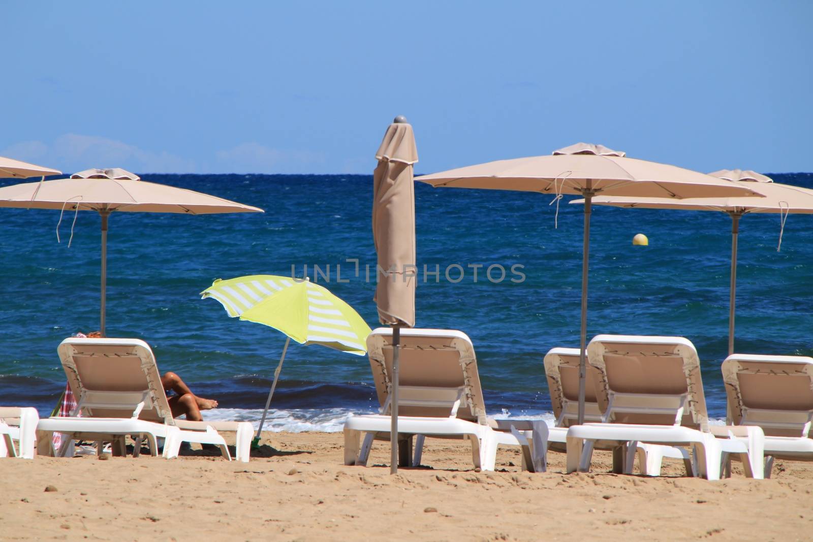 Woman sunbathing on a beach in Alicante and surrounded by sunbeds and umbrellas