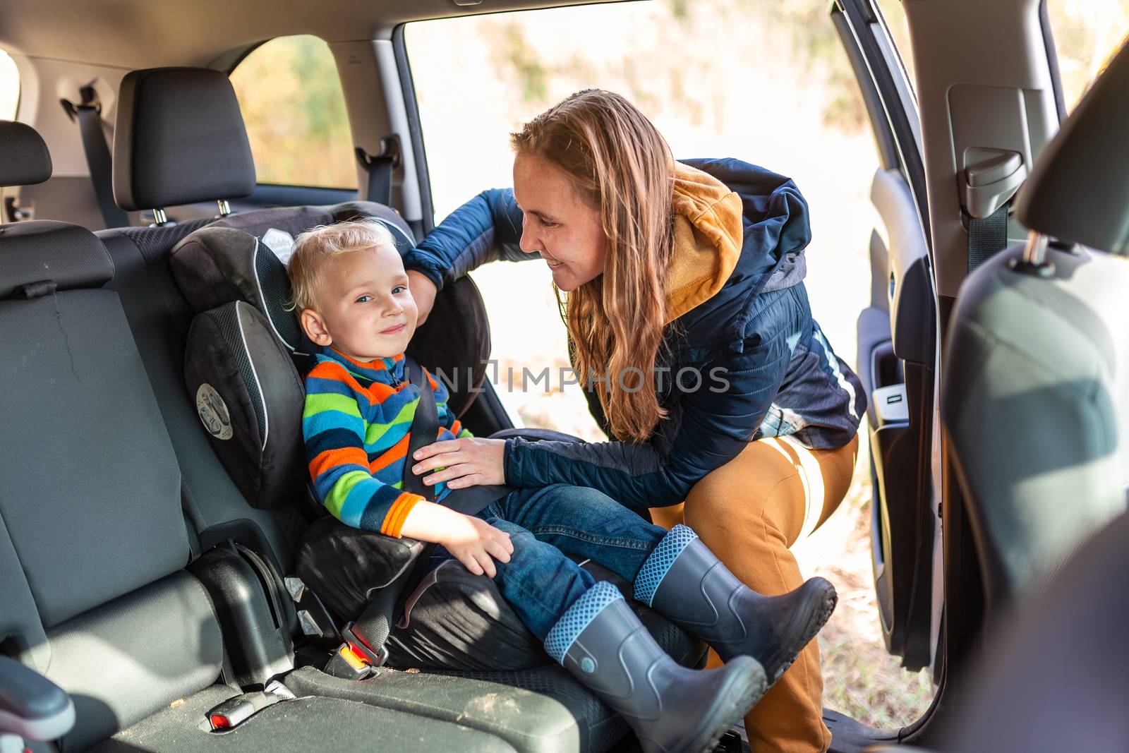 Mother fastening safety belt for her baby boy in his car seat. Children's Car Seat Safety