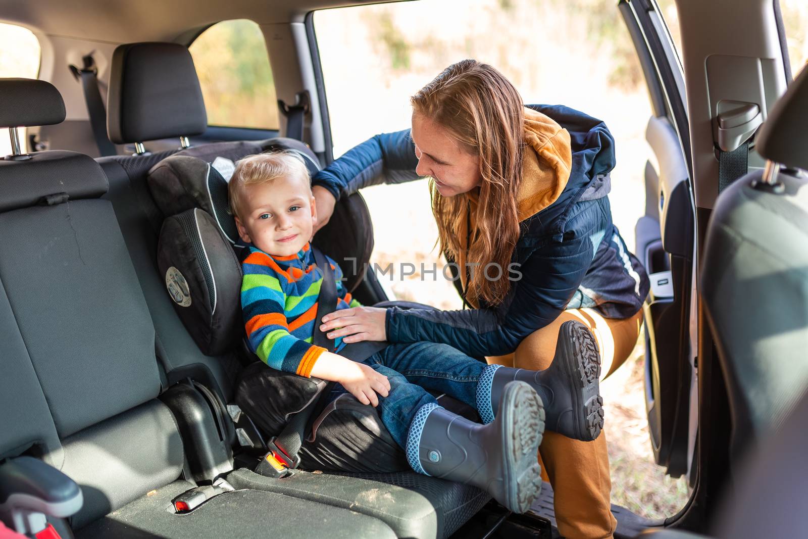 Mother fastening safety belt for her baby boy in his car seat. Children's Car Seat Safety