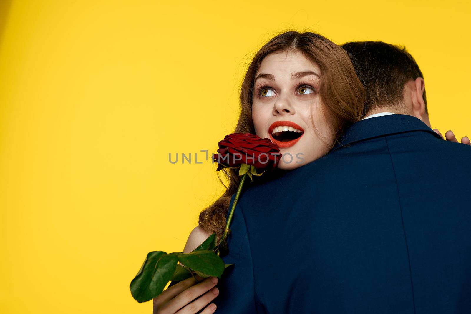 lovers man and woman with a red rose in their hands hugging on a yellow background romance relationship love family by SHOTPRIME