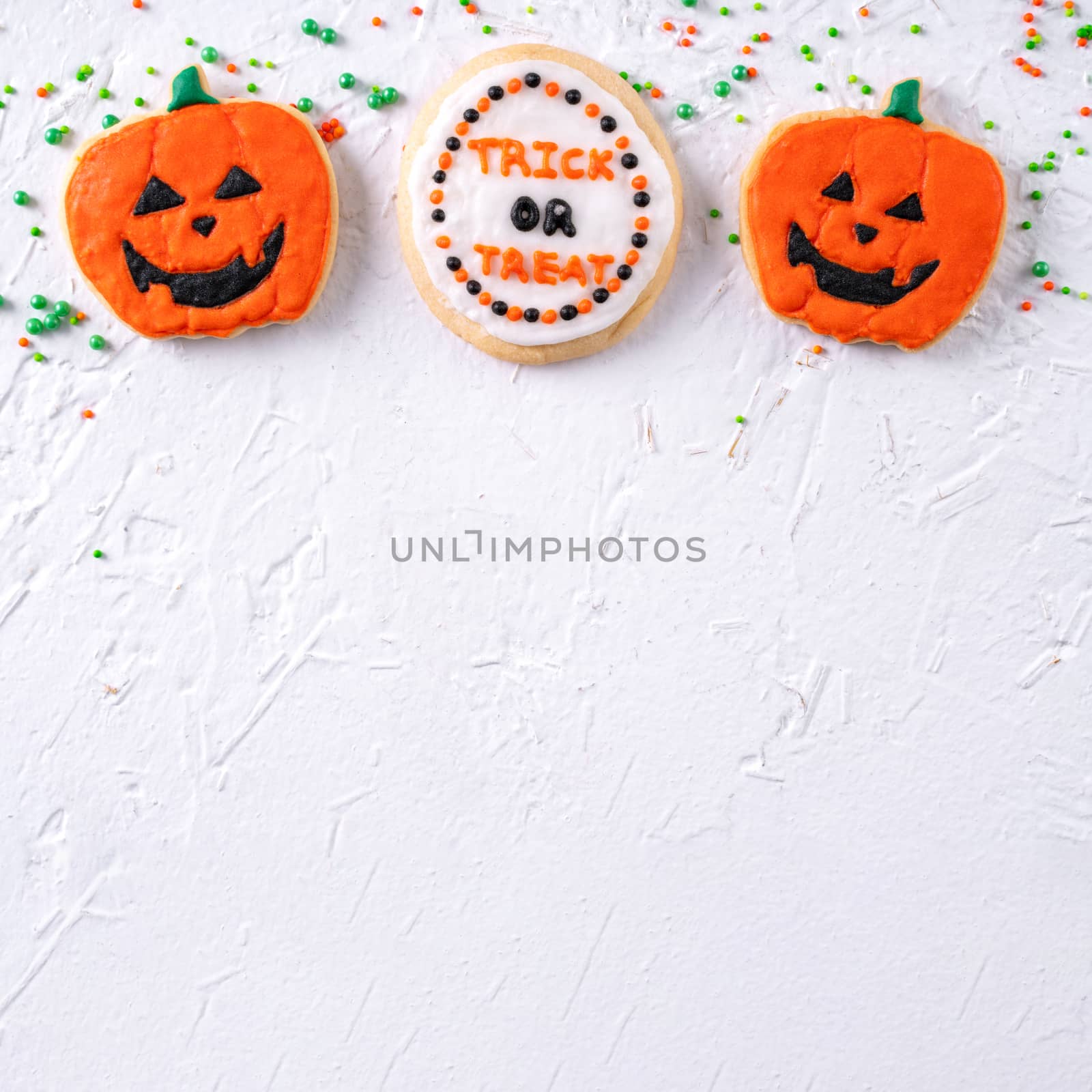 Top view of Halloween festive decorated icing gingerbread sugar cookies on white background with copy space and flat lay layout.