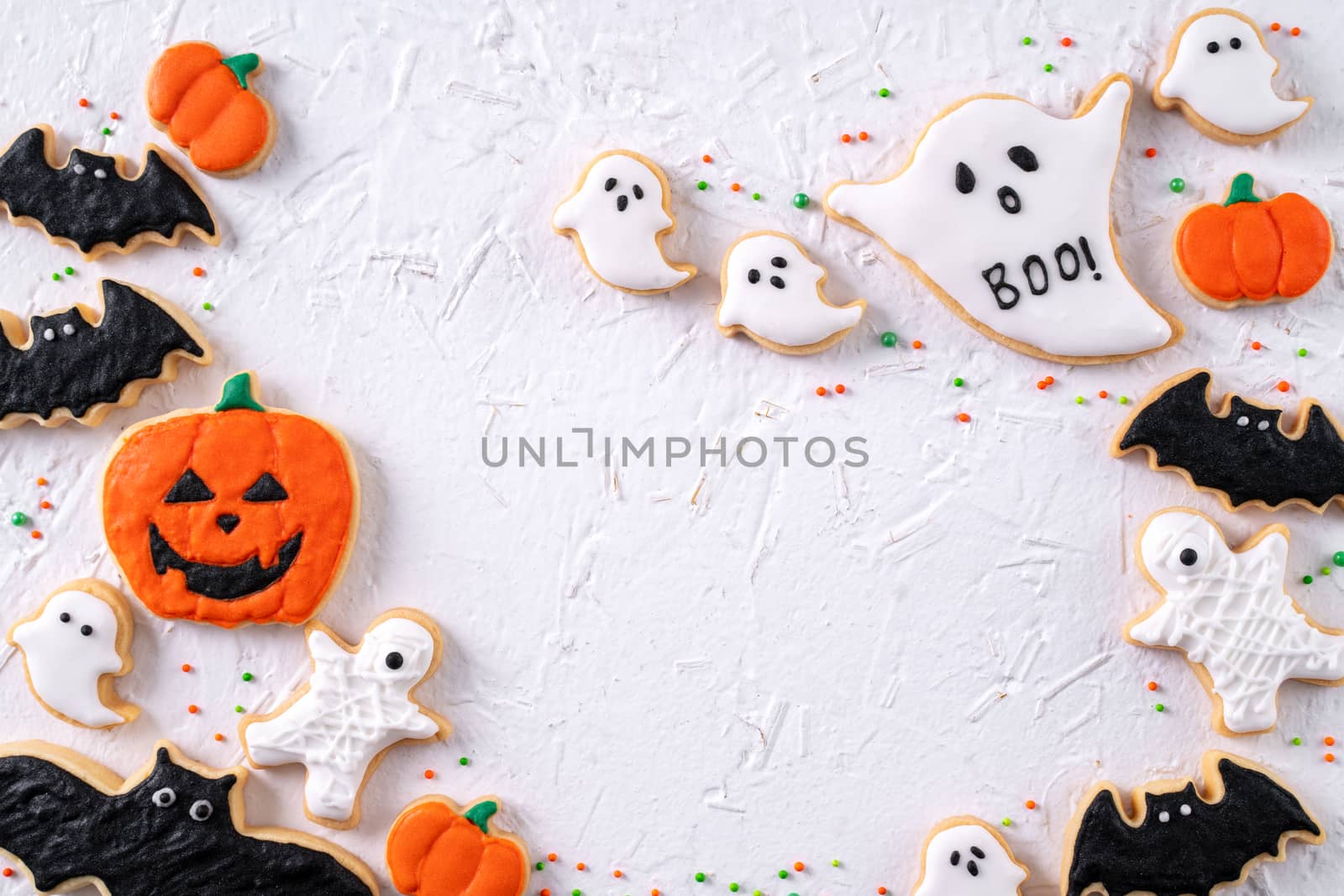 Top view of Halloween festive decorated icing gingerbread sugar cookies on white background with copy space and flat lay layout.