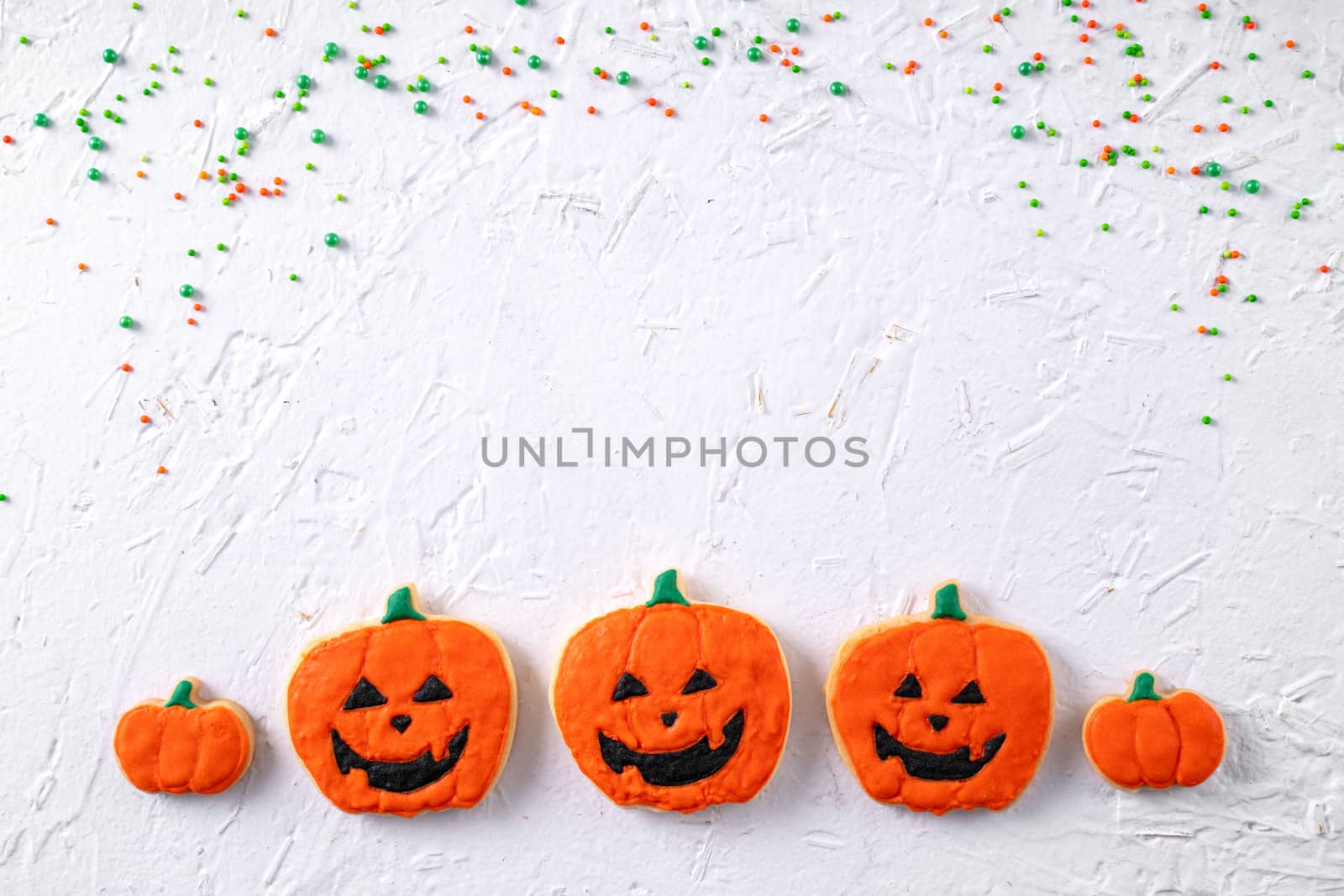 Top view of Halloween festive decorated icing gingerbread sugar cookies on white background with copy space and flat lay layout.