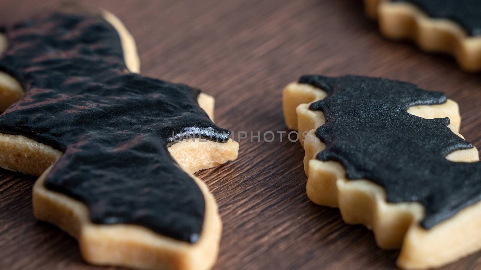 Close up of decorating cute Halloween bat gingerbread sugar cookies with frosting icing cream topping bag.