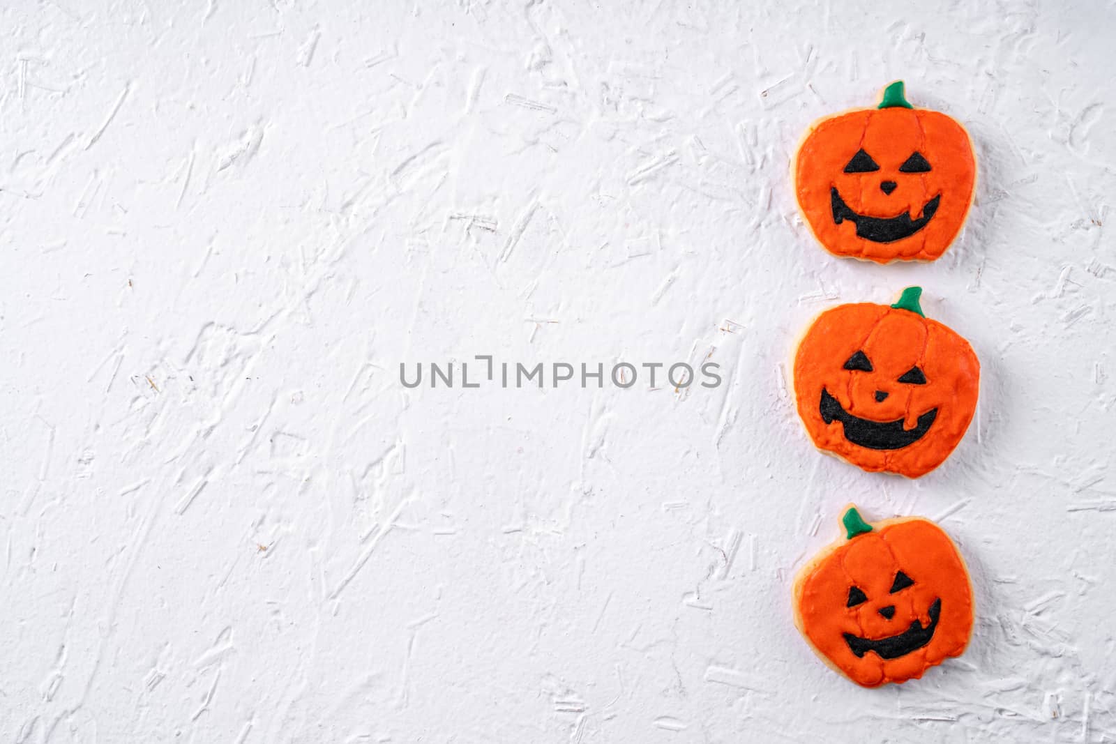 Top view of Halloween festive decorated icing gingerbread sugar cookies on white background with copy space and flat lay layout.