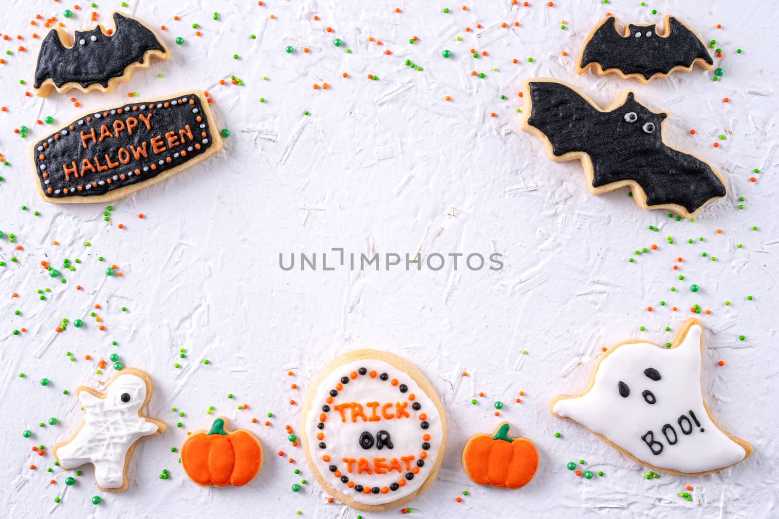 Top view of Halloween festive decorated icing gingerbread sugar cookies on white background with copy space and flat lay layout.