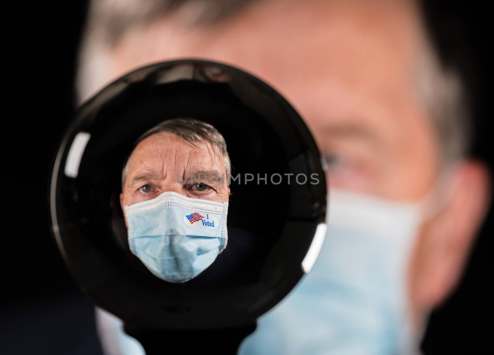 Senior man wearing a medical mask and I Voted sticker inside a glass crystal ball by steheap