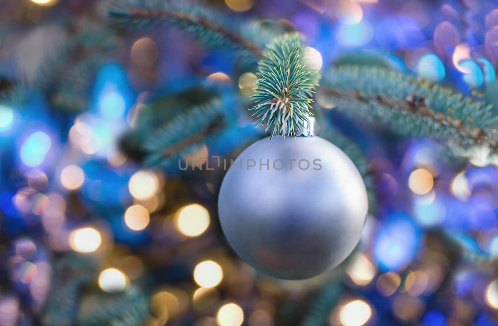 Christmas silver ball decoration ornament. Silver holiday ball hanging from a green christmas tree twig. New year greeting card