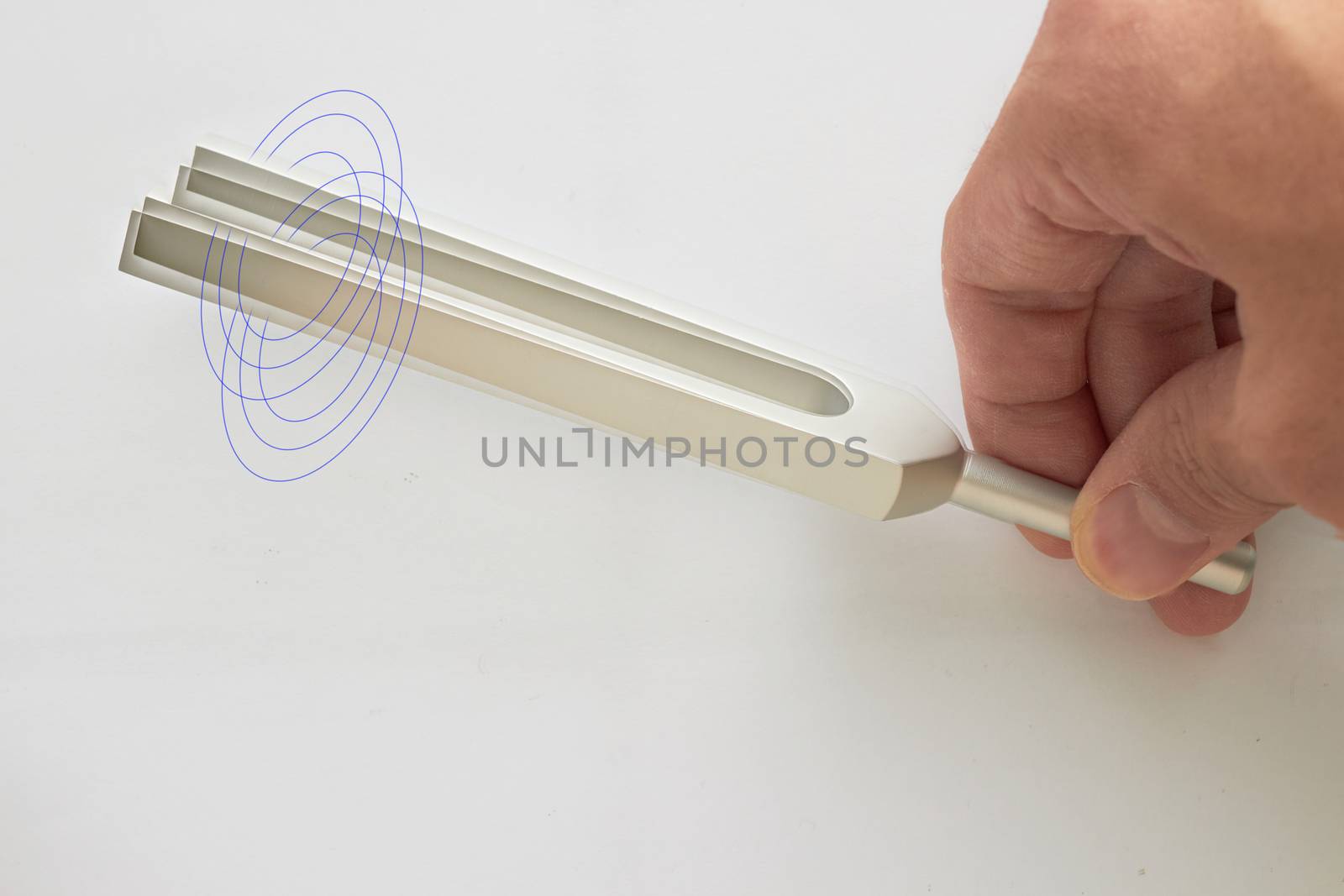 Hand holds Tuning fork for ear test of ENT doctor or sound wave maker on isolated  white background with double exposure