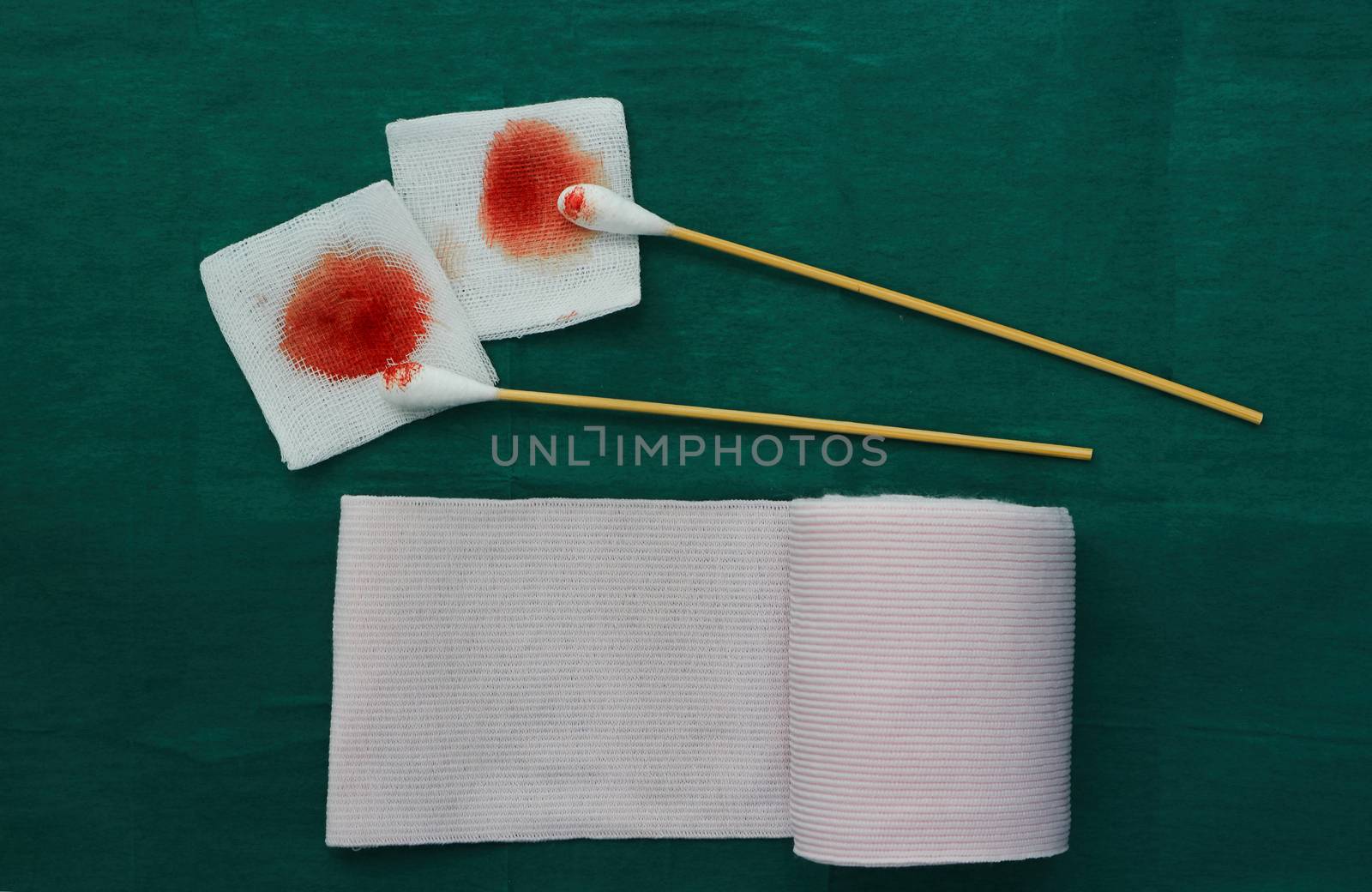 tools include swabs,roll gauze and blood gauze on green surgical dress  for clean wound