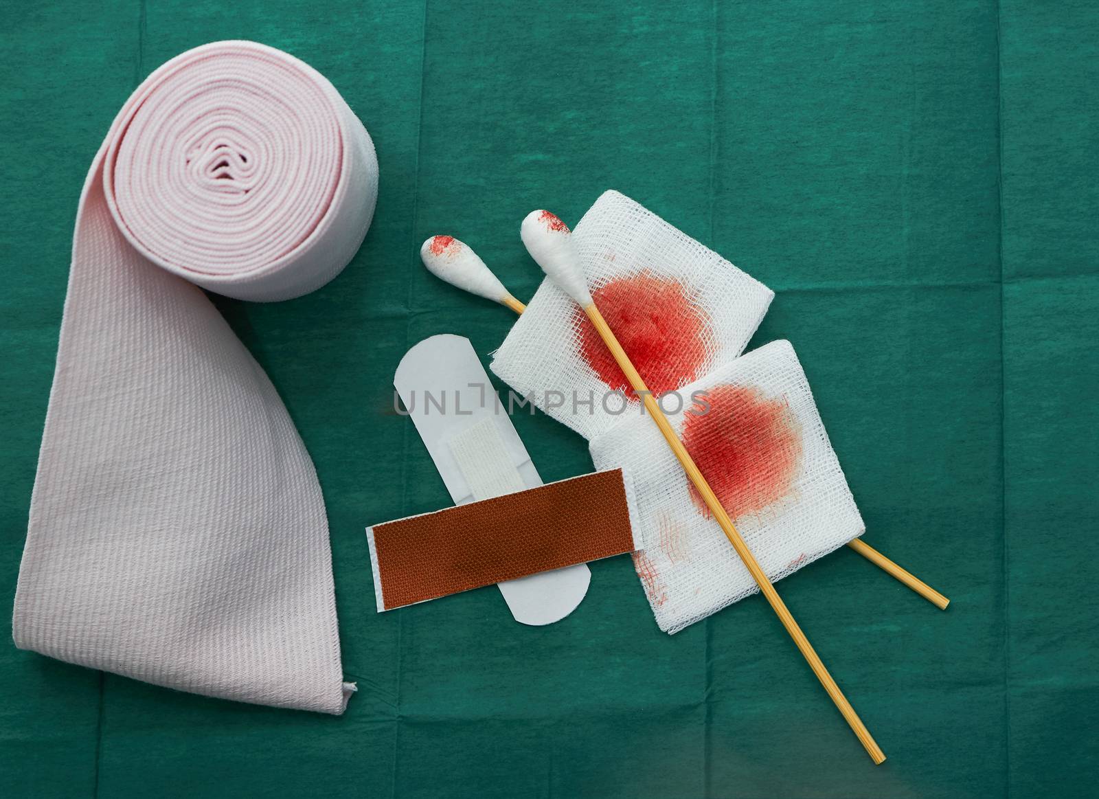 tools include plasters ,swab,blood gauze and roll gauze on green surgical dress  for clean wound